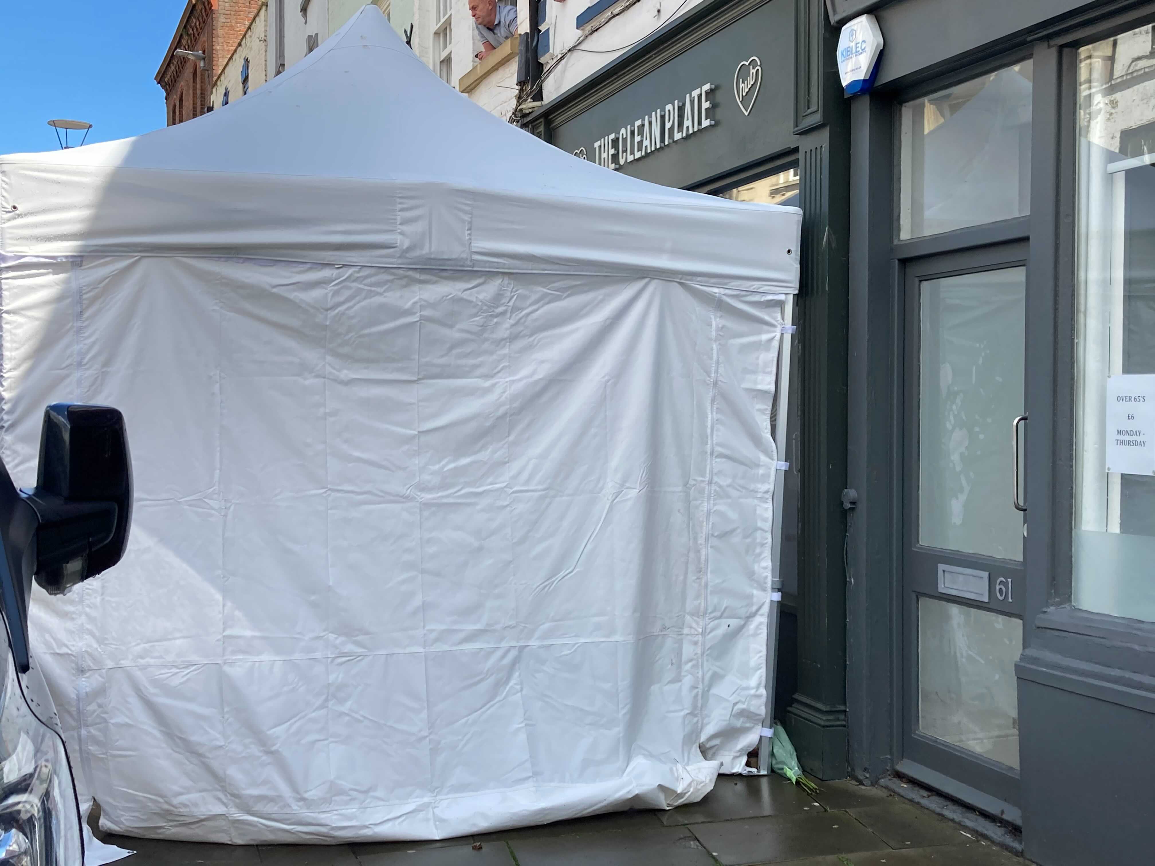 A bouquet of flowers left by the tent outside the Gloucester cafe being excavated by police