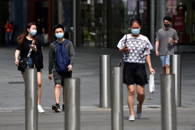 <p>People wearing face masks in Singapore, which has seen a rise in Covid-19 cases</p>