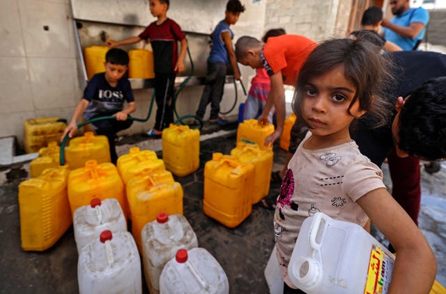 Niños palestinos llenan galones de agua en la ciudad de Gaza