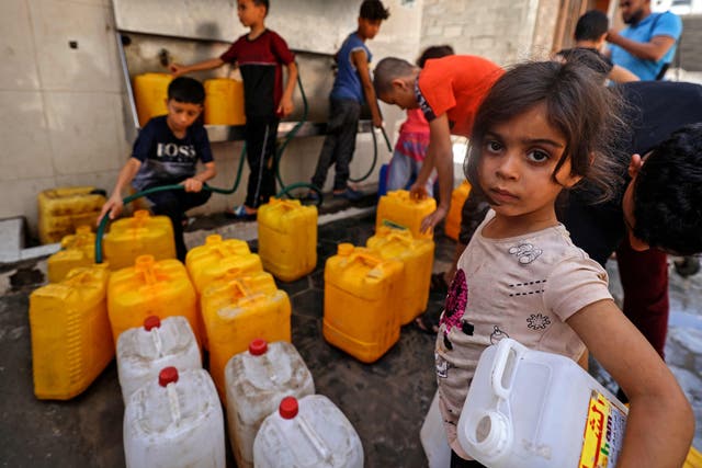 Niños palestinos llenan galones de agua en la ciudad de Gaza