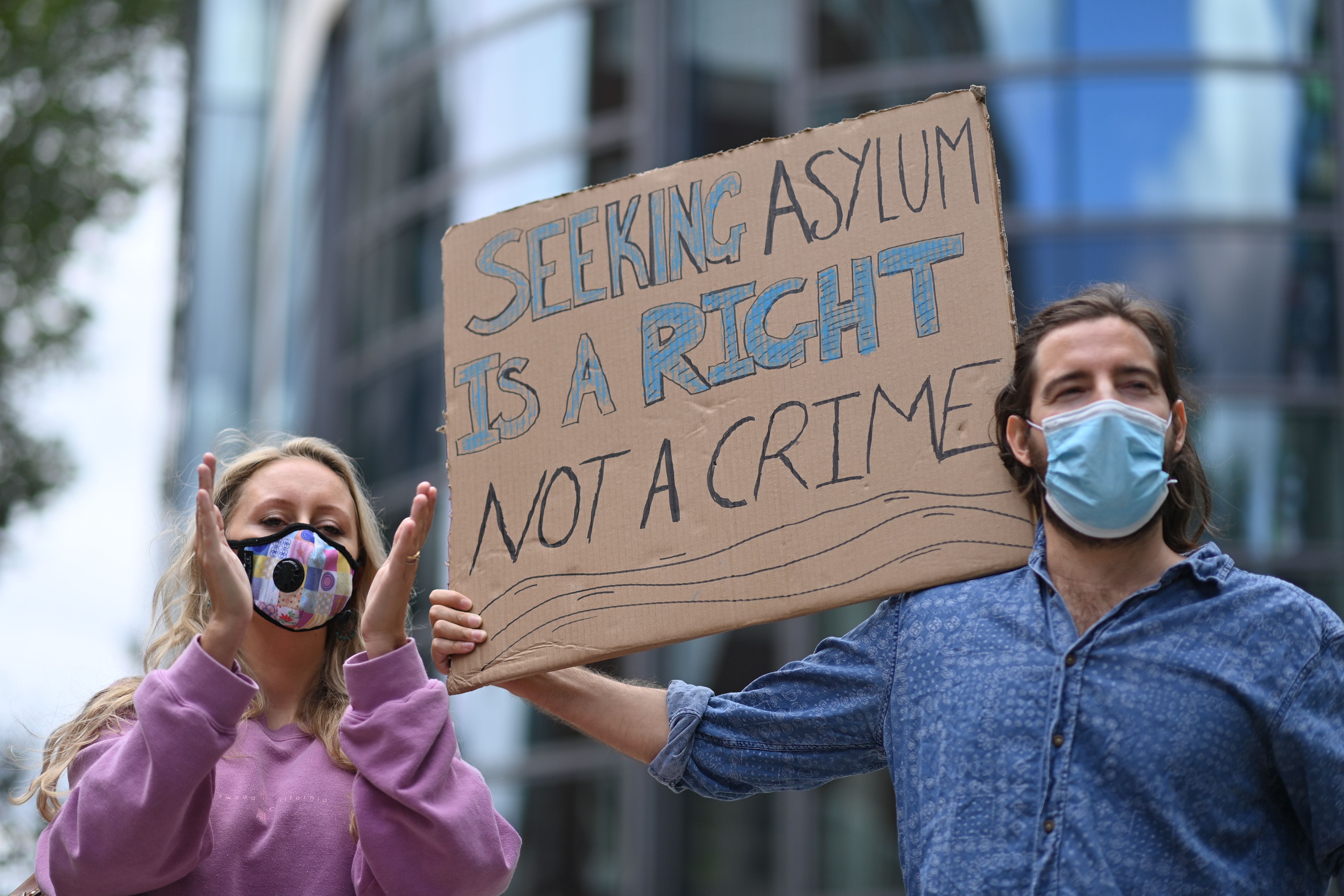 Protesters carry a placard at a demonstration to highlight conditions inside Brook House immigration removal centre and removals, outside the Home Office in London on 23 August, 2020. 