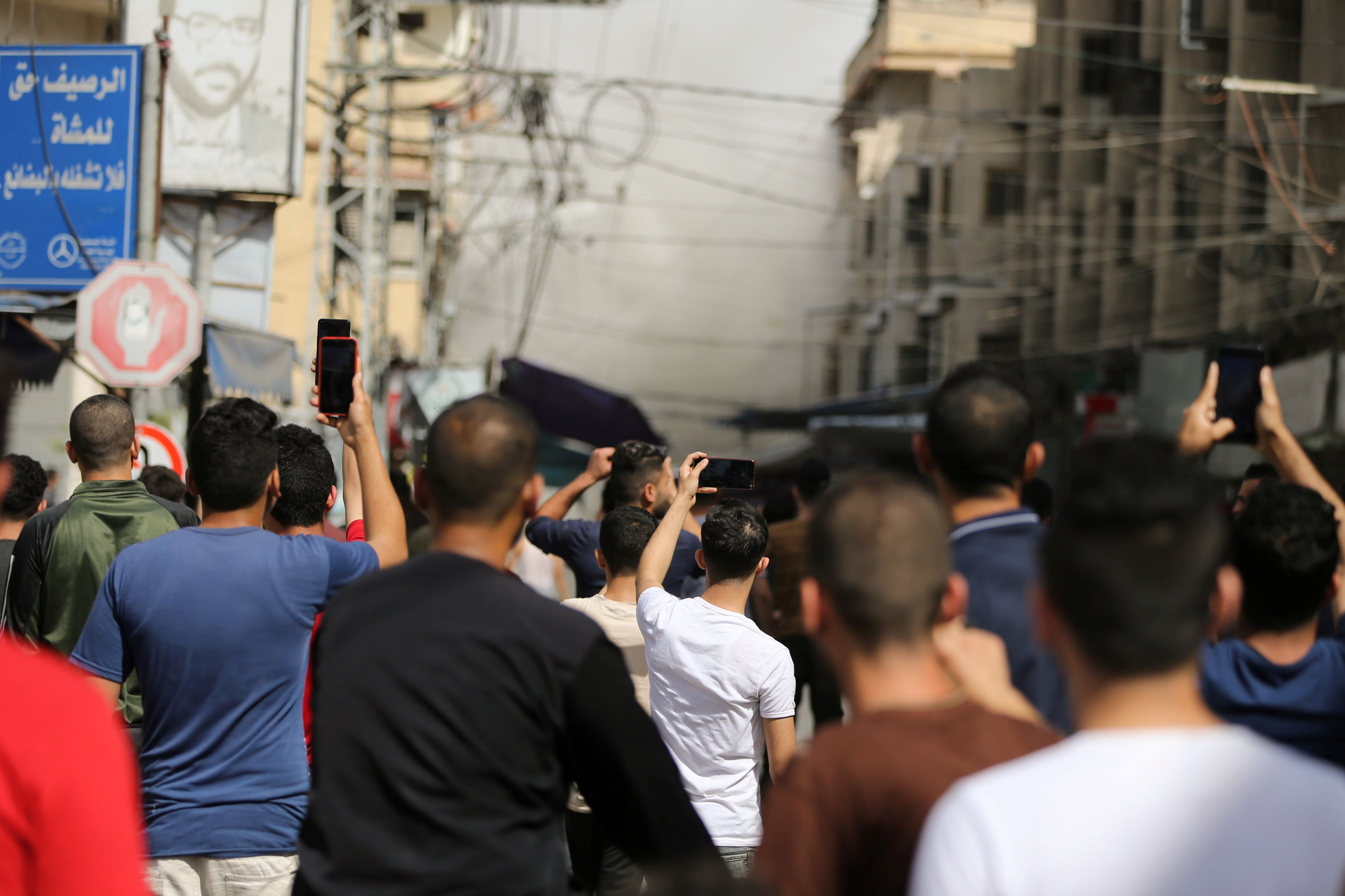 Palestinians gather as smoke rises following an Israeli air strike