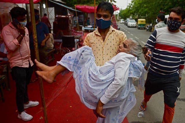 <p>A family member carries a patient, who is having difficulty in breathing, to a free oxygen support centre being run by a Gurdwara, a place of worship for Sikhs, on the outskirts of New Delhi on 10 May</p>