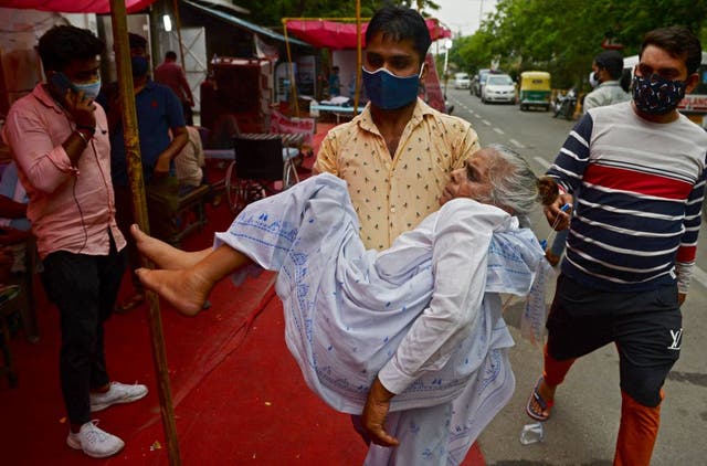 <p>A family member carries a patient, who is having difficulty in breathing, to a free oxygen support centre being run by a Gurdwara, a place of worship for Sikhs, on the outskirts of New Delhi on 10 May</p>