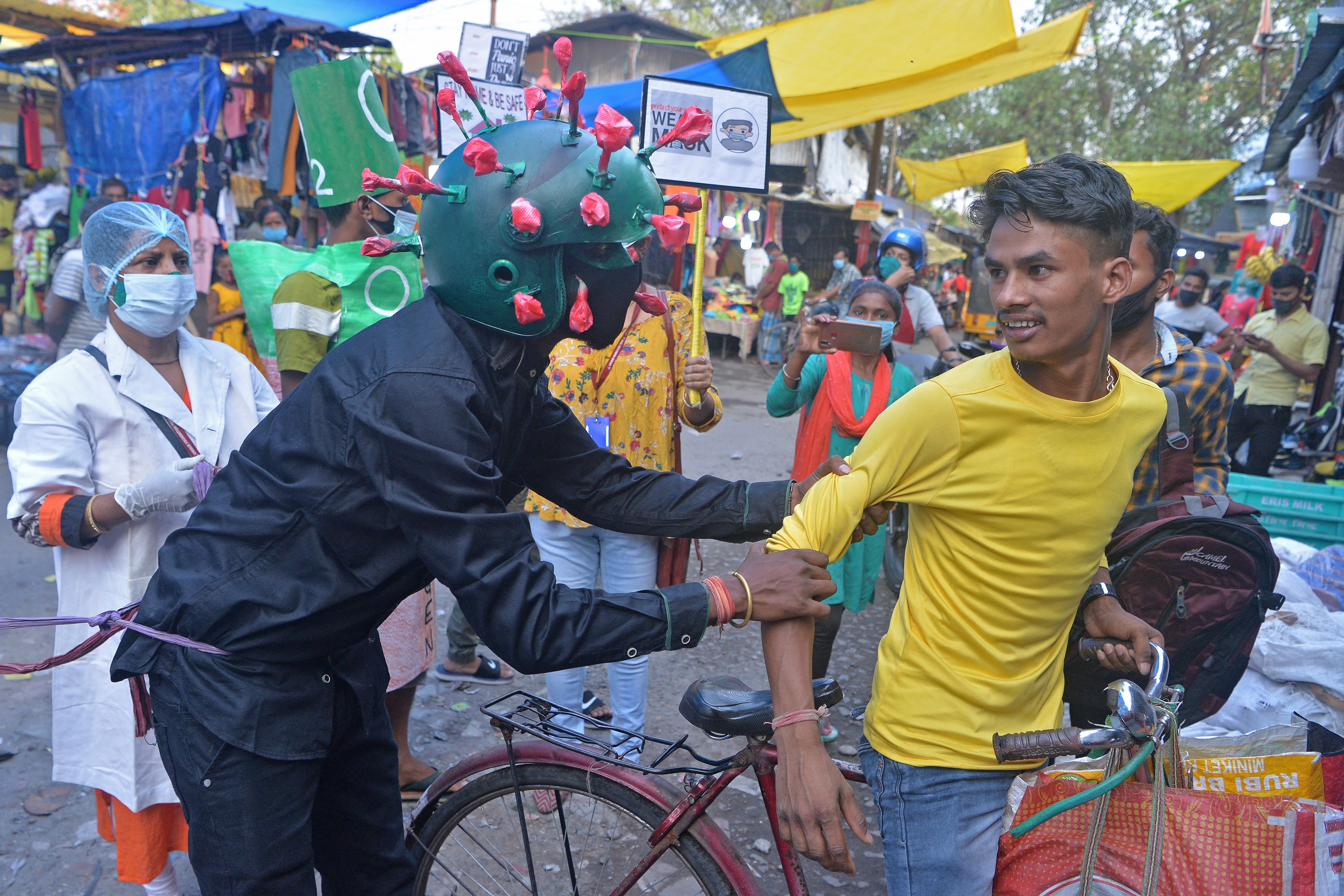 A man from a non-governmental organisation, wearing an outfit resembling the coronavirus, urges people to follow safety protocols in Siliguri on 25 April, 2021