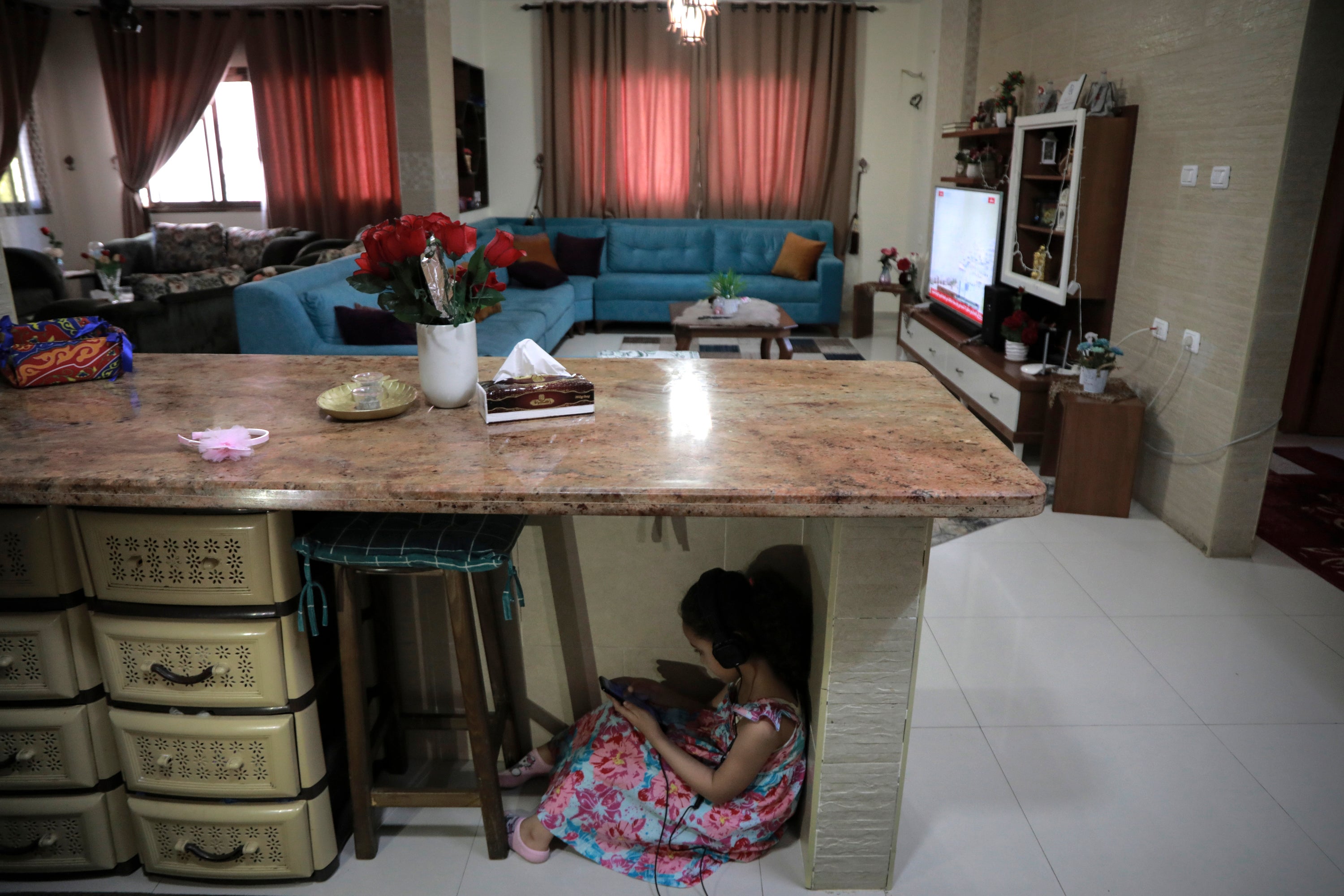 Joury Mghames, seven, hides under a counter in the kitchen of her home in Gaza City during Israeli bombing