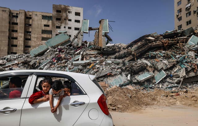 Palestinians drive past the Al-Jalaa Tower in Gaza City, a building that hosted the offices of the Associated Press news agency as well as the Al-jazeera English television channel, levelled by an Israeli air strike.