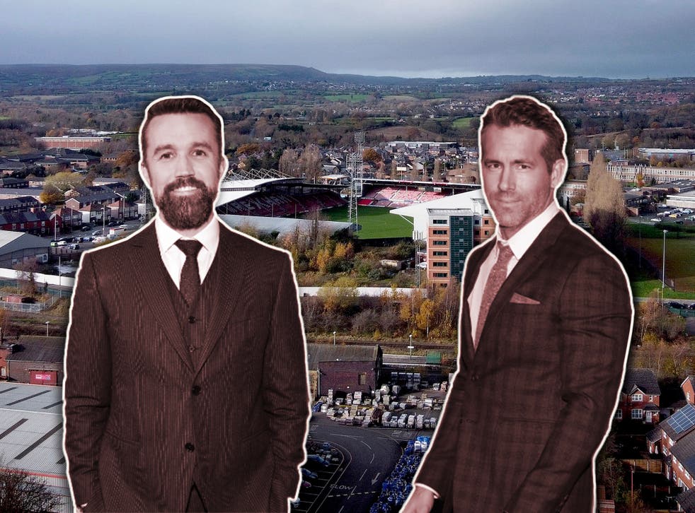 <p>Firing up the Red Dragons: new owners Rob McElhenney (left) and Ryan Reynolds, with Wrexham’s Racecourse Ground behind</p>