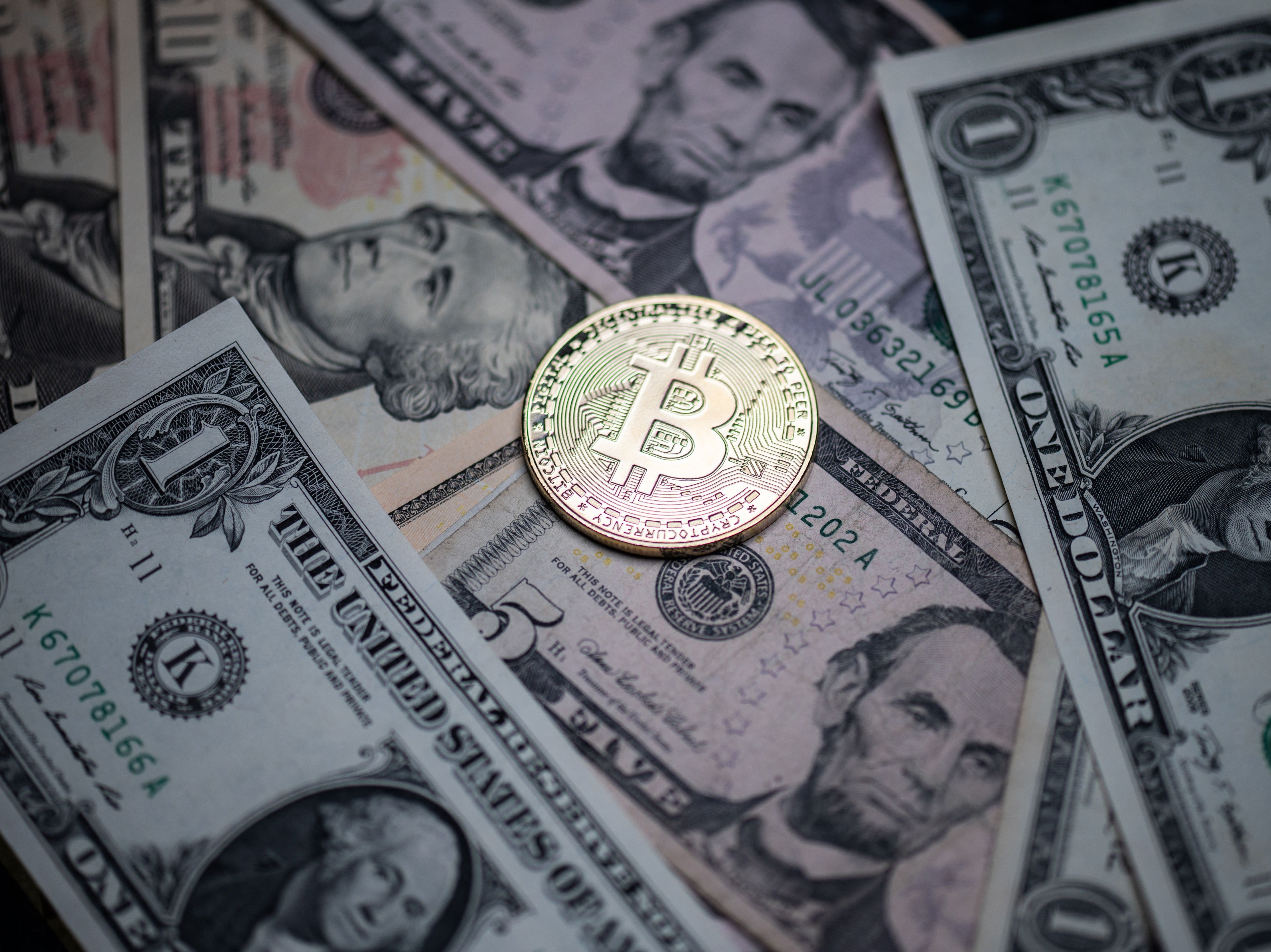 A physical imitation of the Bitcoin crypto currency displayed on US dollars bank notes