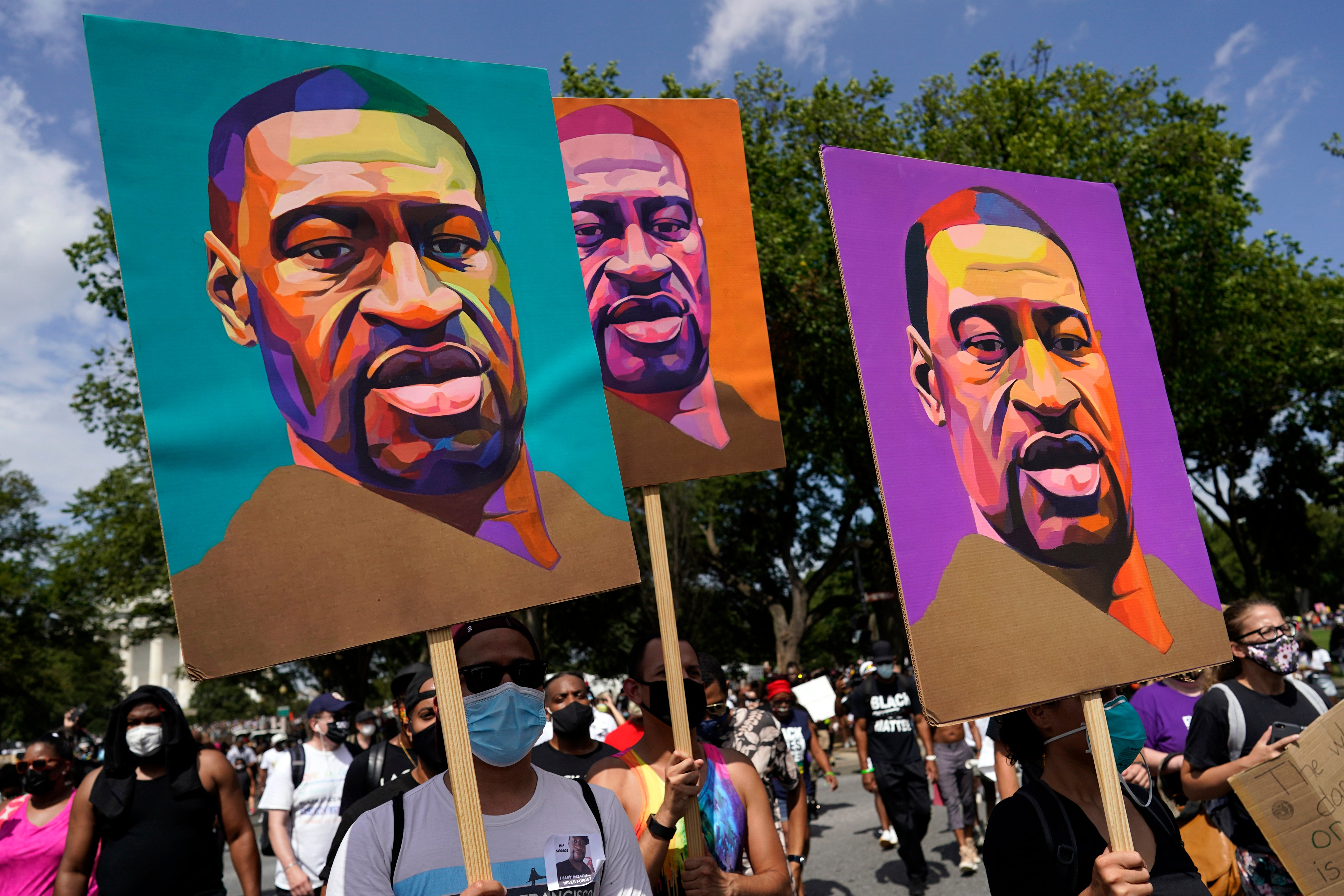 FILE - In this 28 August, 2020, file photo, people carry posters with George Floyd’s image on them as they march from the Lincoln Memorial to the Martin Luther King Jr Memorial in Washington. As the anniversary of George Floyd’s murder approaches, a poll has revealed that Black Americans are more likely to experience potentially dangerous interactions with the police