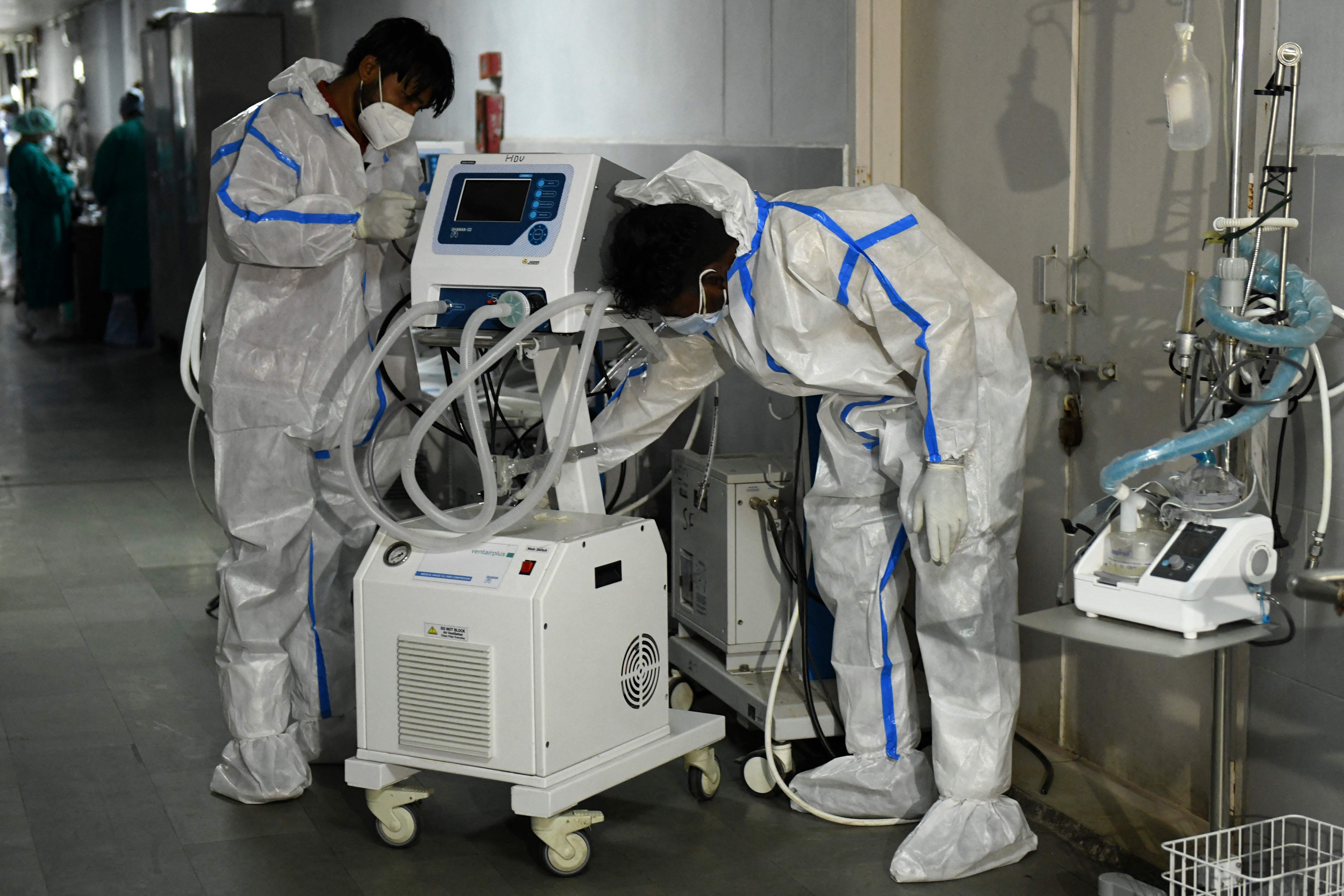Health workers wearing protective gear place a defunct ventilator machine in the corridor of a hospital amid Covid-19 coronavirus pandemic in Amritsar