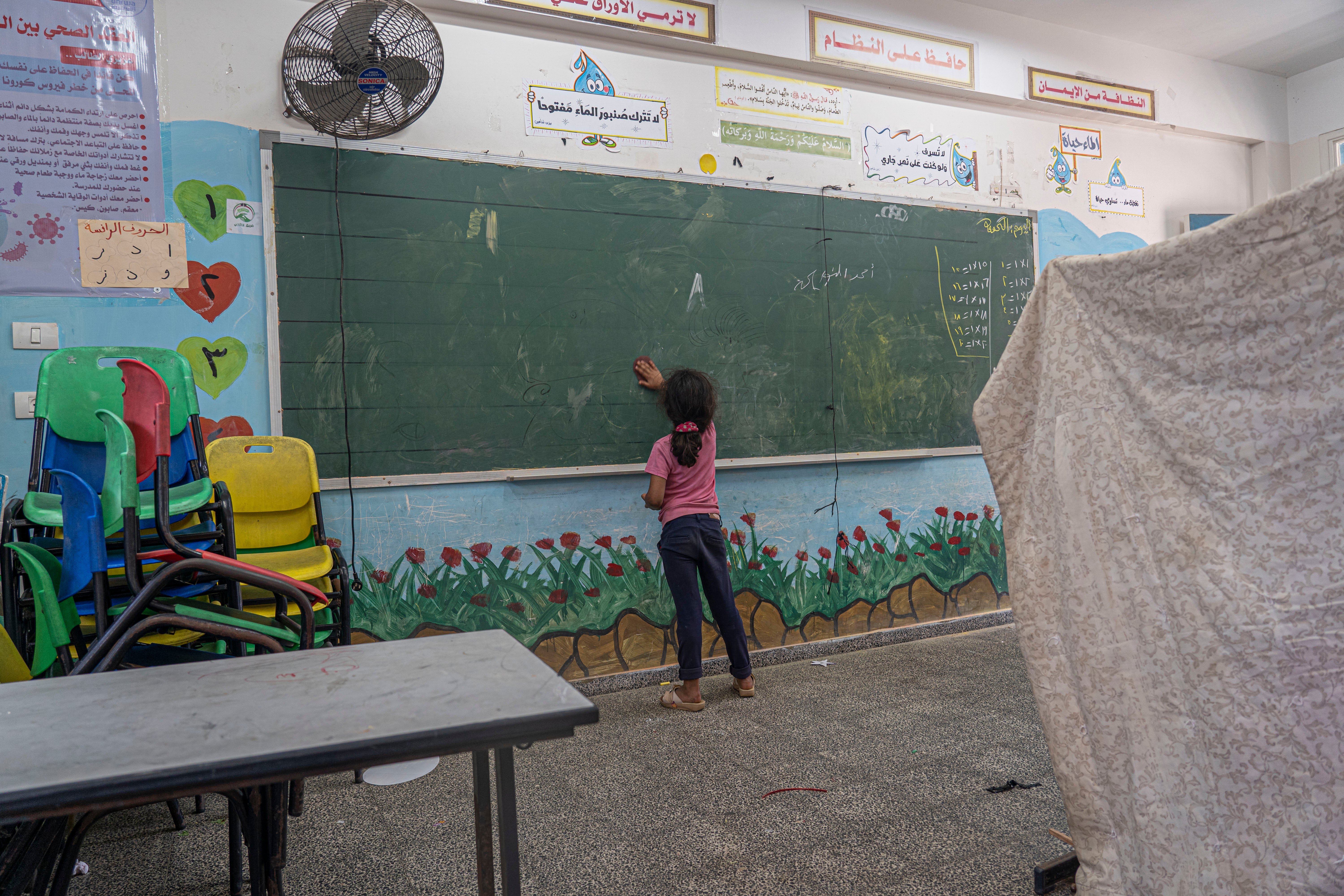 A child plays with the blackboard in a UNRWA boy’s school turned into a shelter for Gaza’s displaced