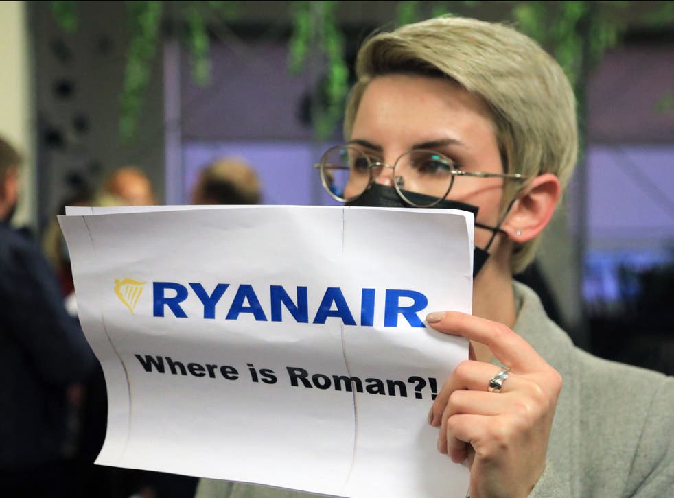A woman stands with a poster reading ‘Where is Roman [Protasevich]?!’ in the arrival area as passengers disembark from a Ryanair passenger plane from Athens