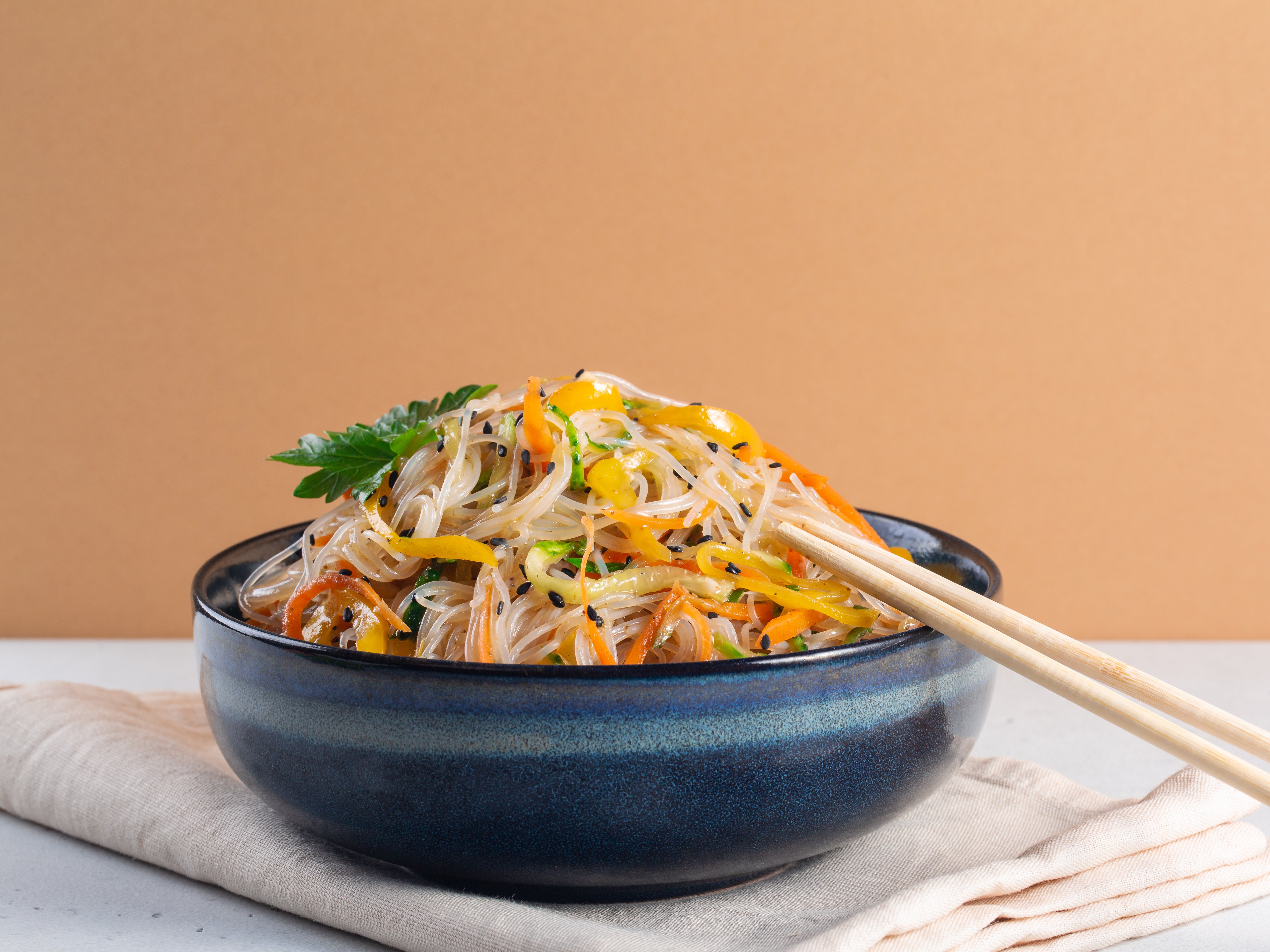 Japchae is a savoury Korean stir-fry with mixed vegetables, beef and sweet potato noodles