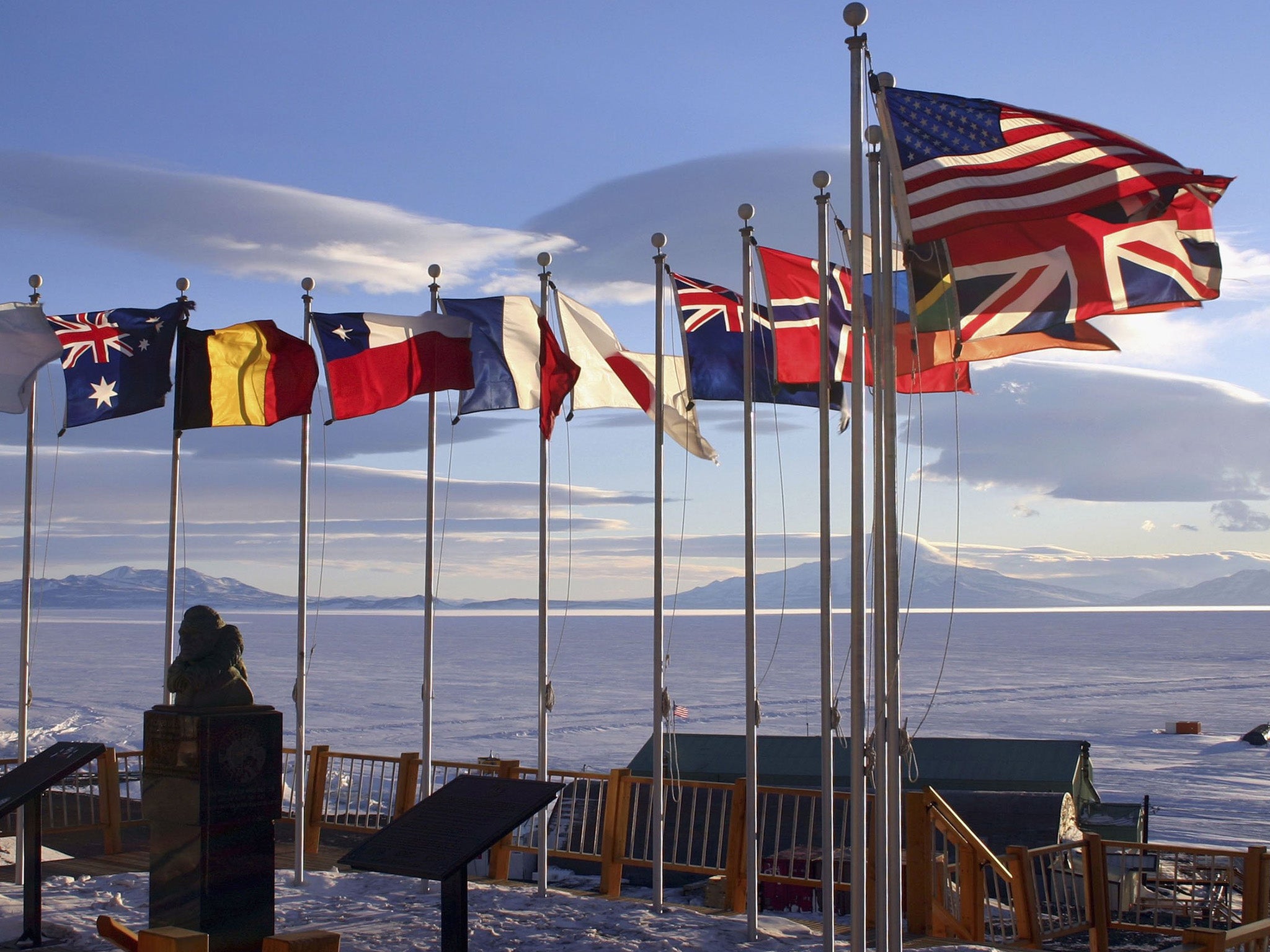 Flags of the original 12 signatory nations of the Antarctic Treaty fly next to a bust of Admiral Richard Byrd at McMurdo Station in 2005