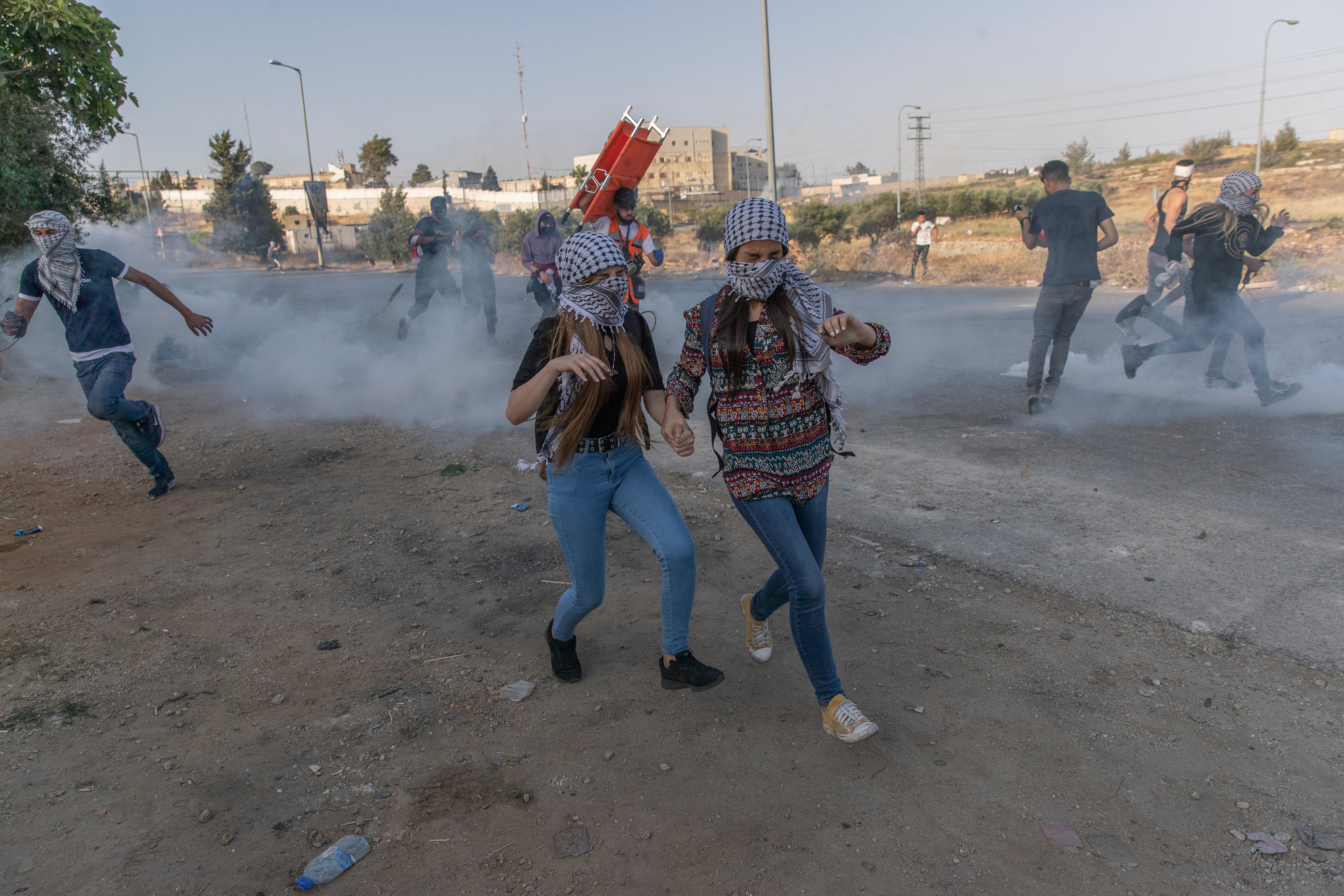 Palestinian protesters run to avoid teargas during clashes with Israeli soldiers at the northern entrance of the West Bank city of Ramallah