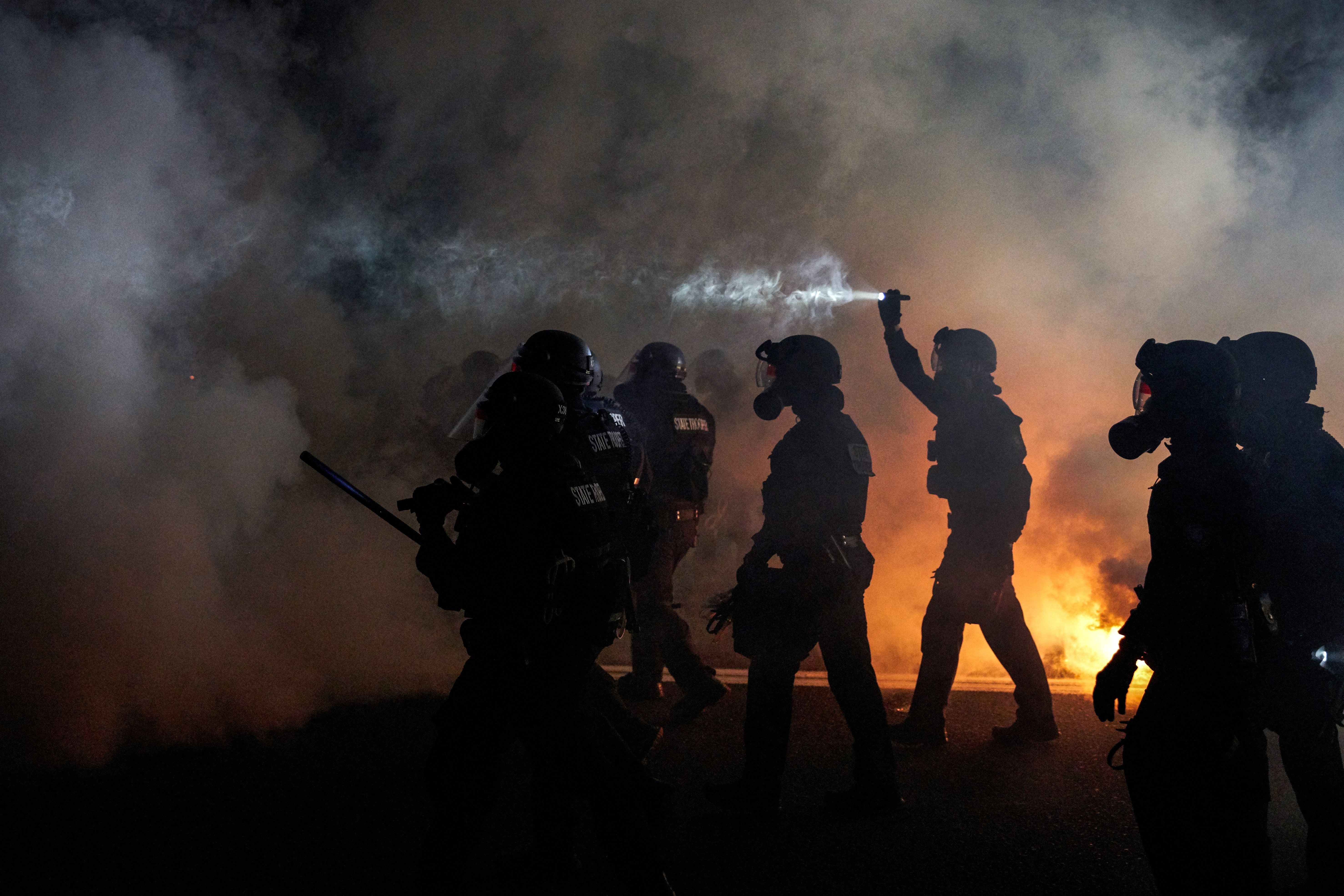 Oregon Police wearing anti-riot gear march towards protesters through tear gas smoke during the 100th day and night of protests against racism and police brutality in Portland, Oregon, on September 5, 2020