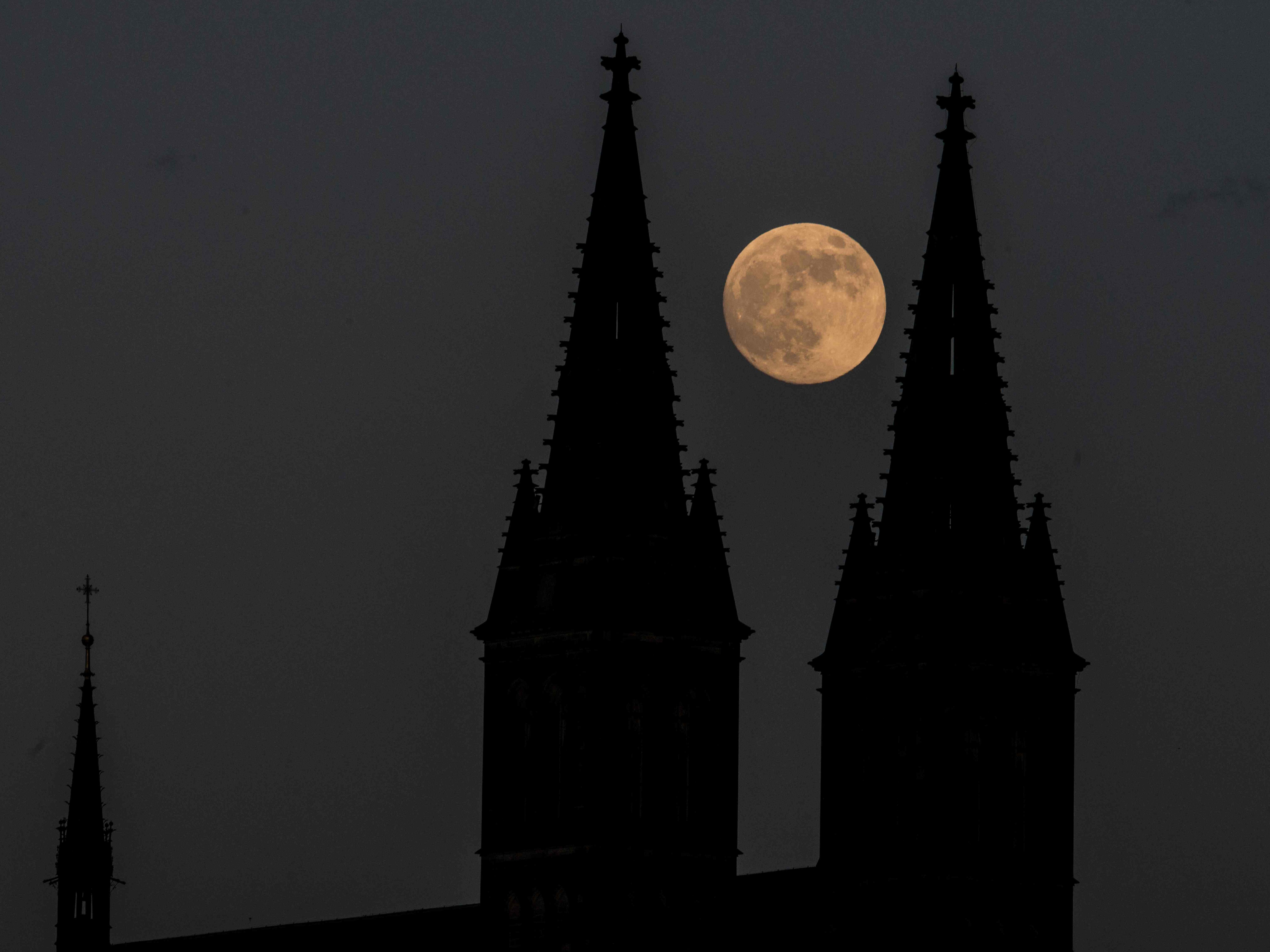 The full moon rising behind the of Basilica of St Peter and St Paul, part of Vysehrad Castle, in Prague, Czech Republic, on Tuesday 25 May 2021