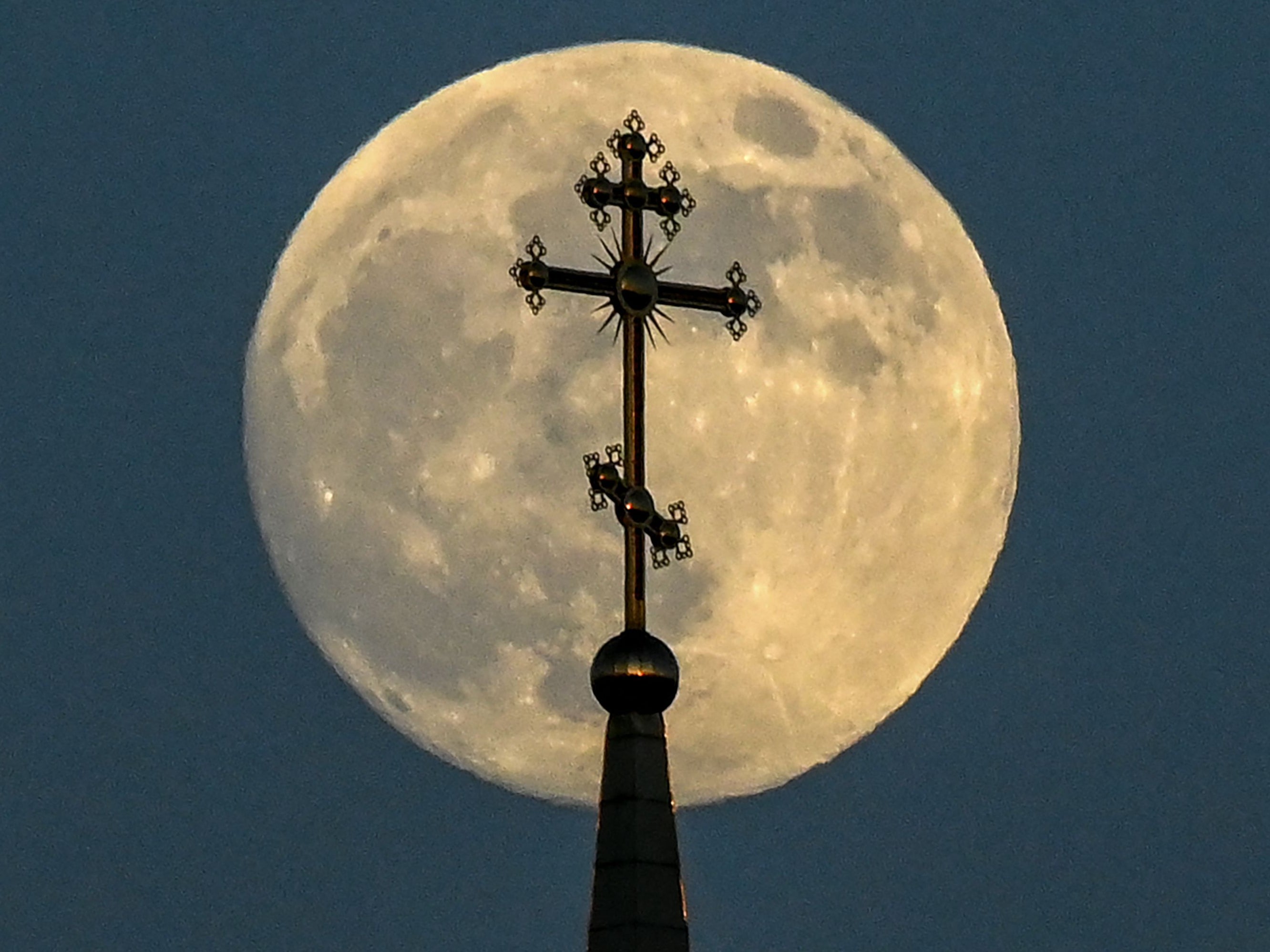 The full moon behind a cross on top of an orthodox church in the city of Rossosh in Voronezh, Russia, on Tuesday 25 May 2021