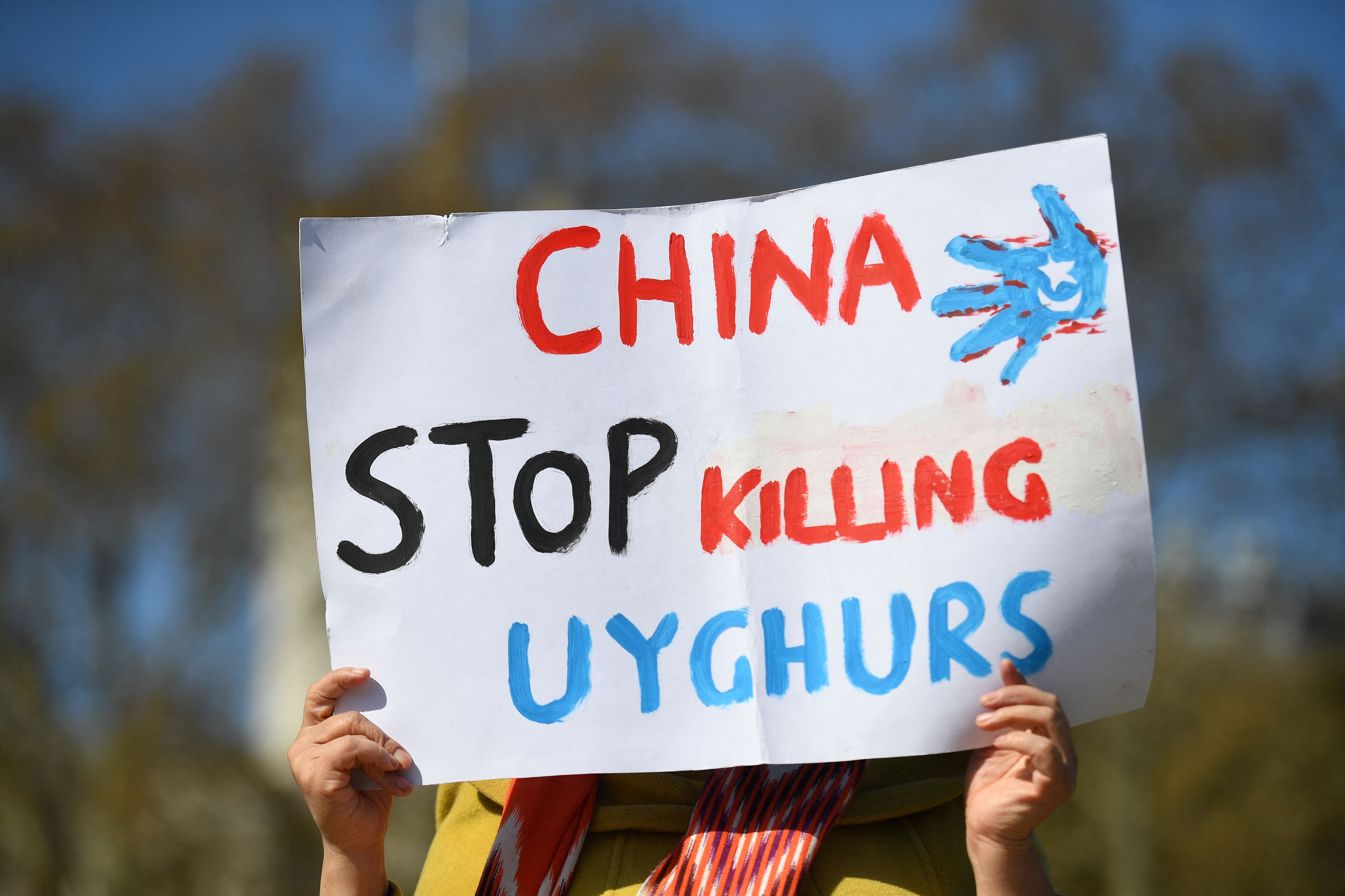 A member of the Uighur community holds a placard as she joins a demonstration to call on the British parliament to vote to recognise alleged persecution of China's Muslim minority people as genocide and crimes against humanity in London on April 22, 2021
