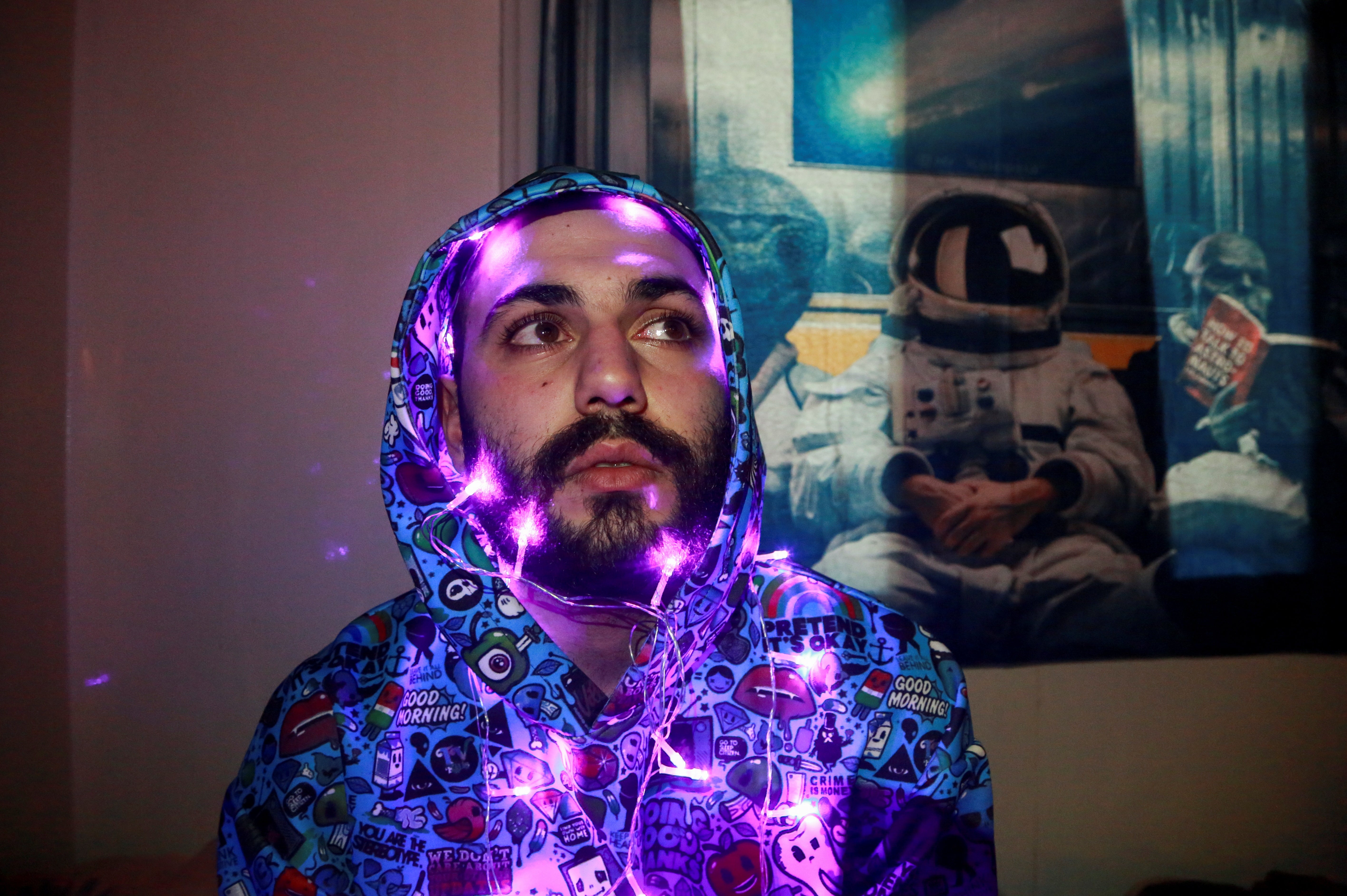 Ali, an IT student, poses for a photograph with lights wrapped around his head, in Damascus