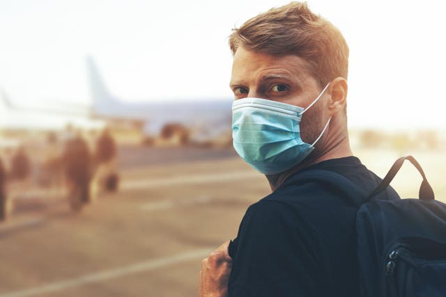 Man in face mask about to board a plane