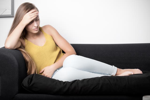 <p>Woman lying on a couch with pain in her stomach</p>