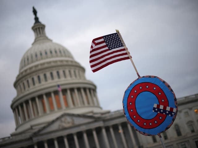 <p>Trump supporters fly a US flag with a symbol denoting QAnon as they gather outside the US Capitol on 6 January</p>