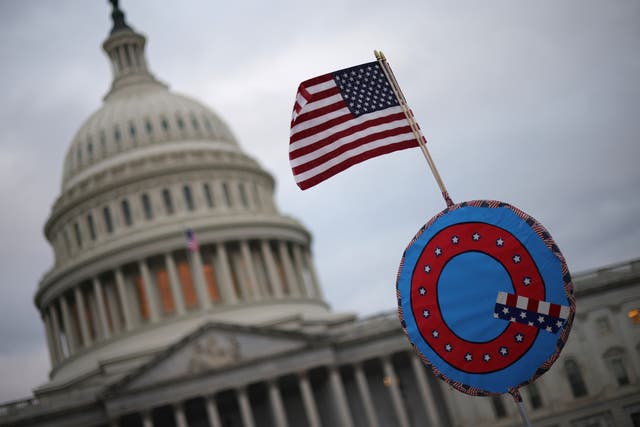 <p>Los partidarios de Trump enarbolan una bandera estadounidense con un símbolo que denota QAnon mientras se reúnen frente al Capitolio de los Estados Unidos el 6 de enero.</p>