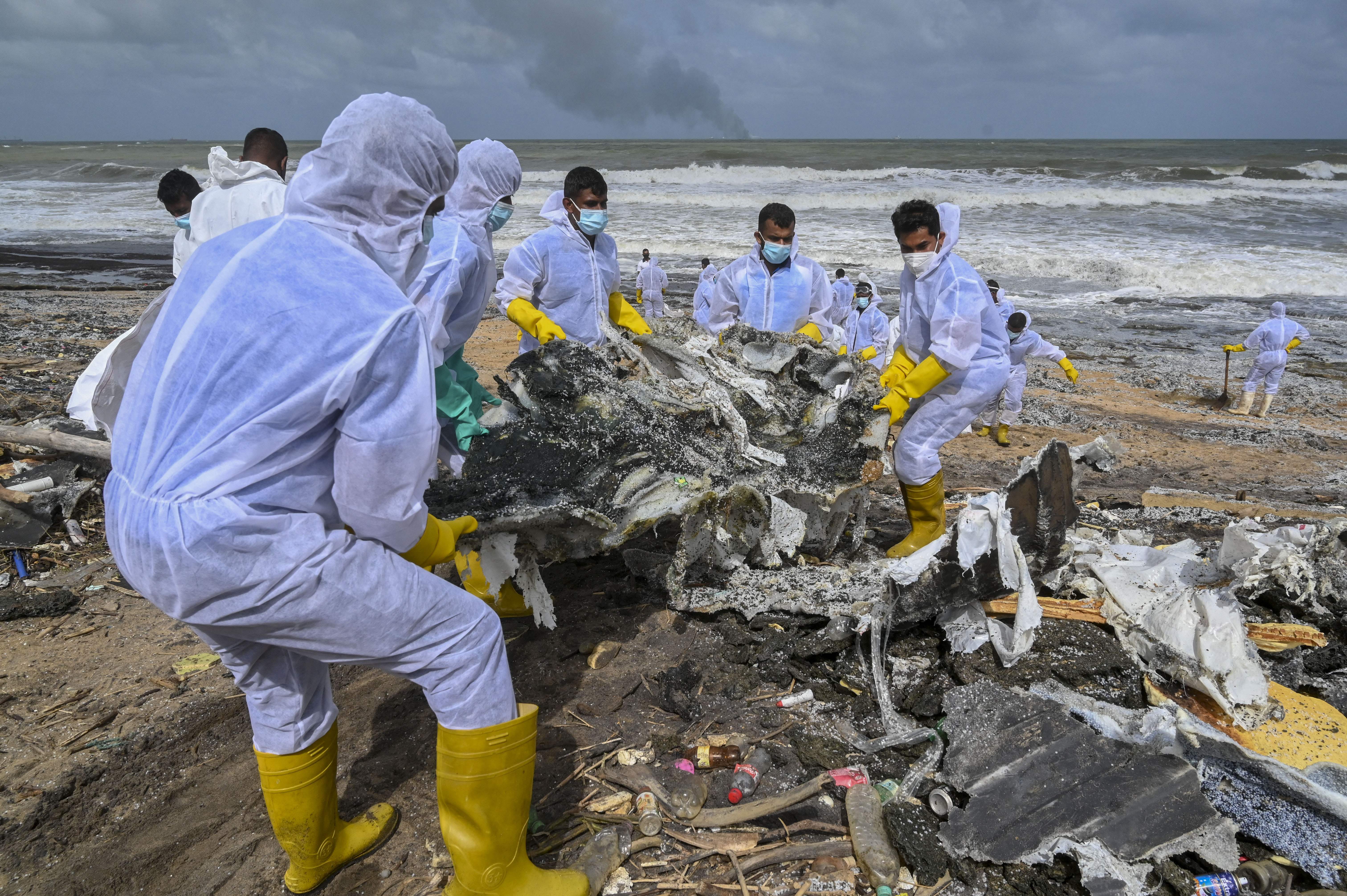 Sri Lankan Navy soldiers work to remove debris washed ashore from the Singapore-registered container ship MV X-Press Pearl, which has been burning for the eighth consecutive day in the sea off Sri Lanka’s Colombo Harbour, on a beach in Colombo on May 28, 2021. (Photo by Ishara S. KODIKARA / AFP) (Photo by ISHARA S. KODIKARA/AFP via Getty Images)