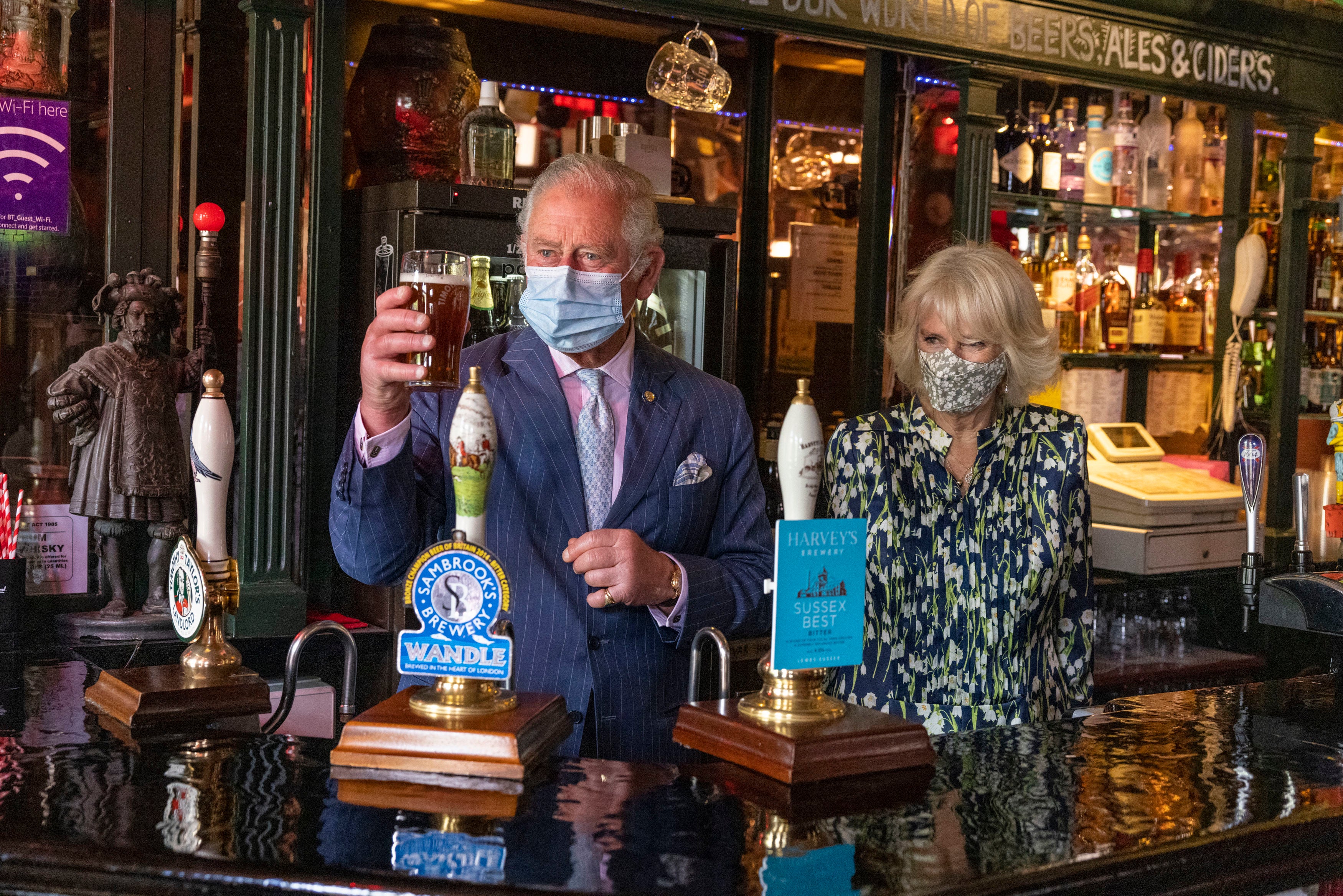 Charles and Camilla stand behind the bar after the former prince pulled a pint, during a visit to Clapham Old Town, to celebrate the reopening of non-essential shops as Covid coronavirus restrictions were eased