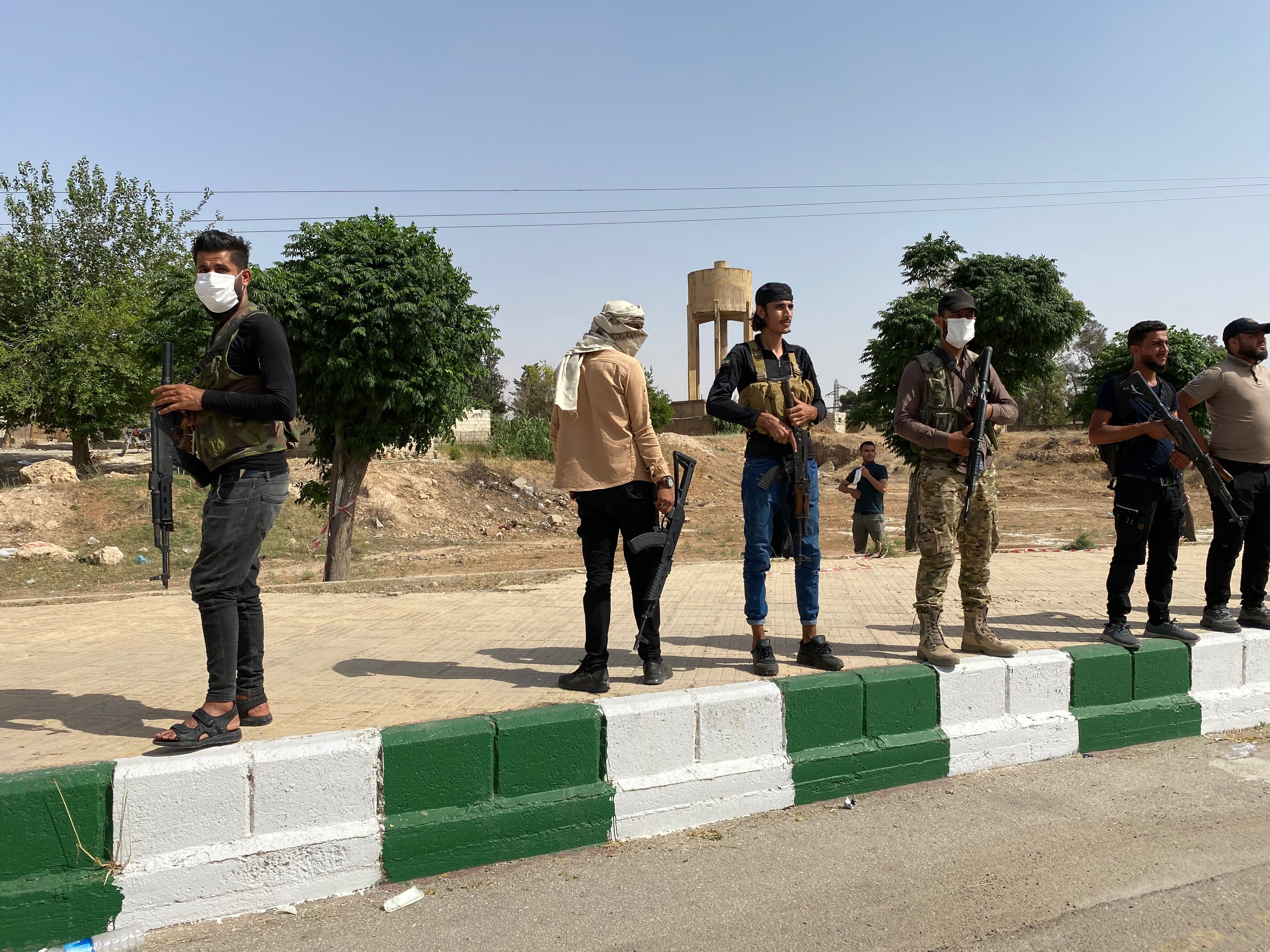 Turkish-backed Syrian militiamen stand guard near a water tower in Tal Abyad