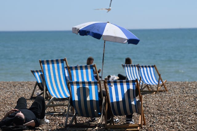 <p>People sit in deckchairs looking out onto the channel on Brighton</p>