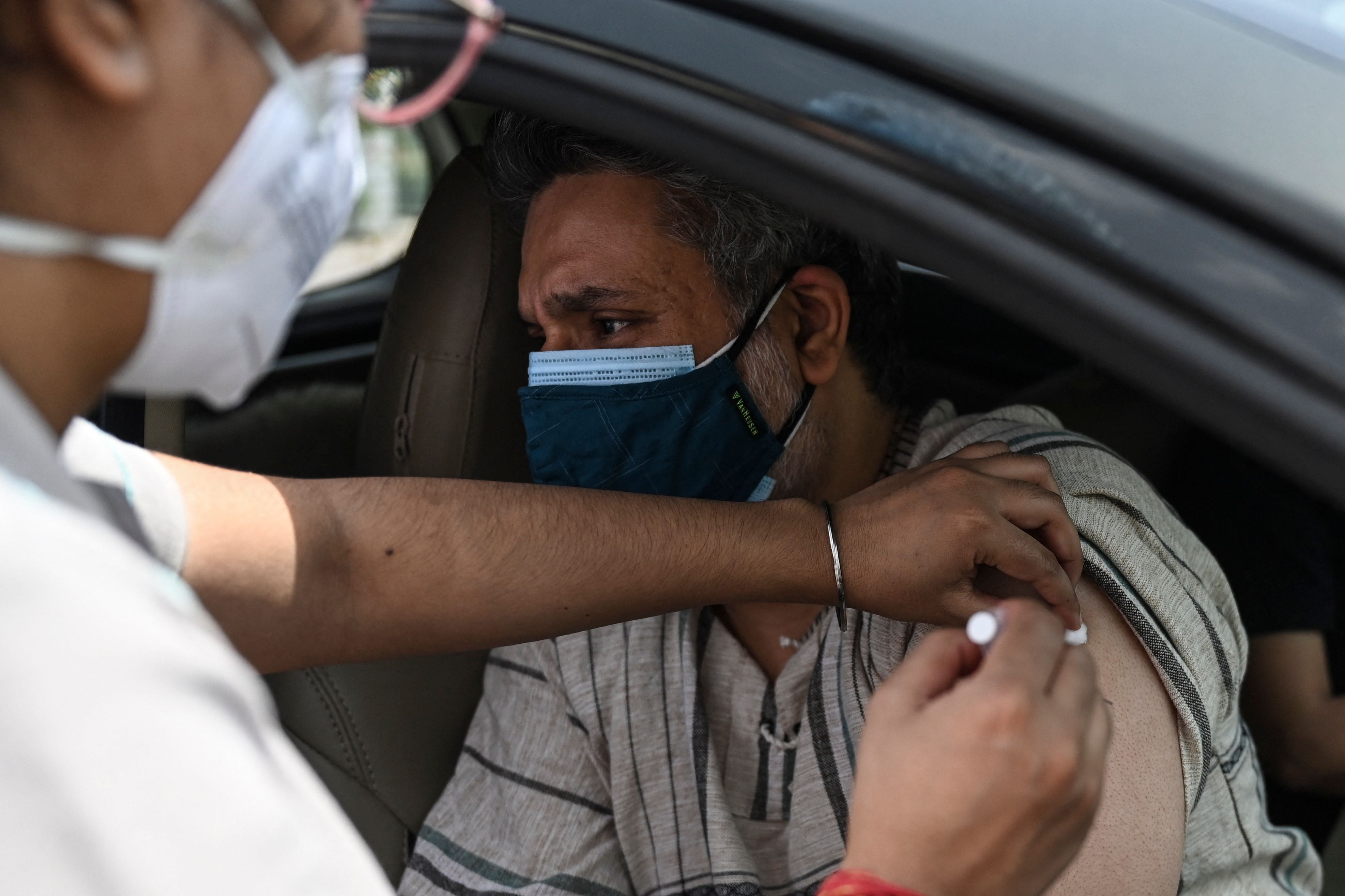 A health worker inoculates a man at a drive-through vaccination centre in New Delhi on 30 May, 2021.