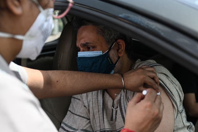 <p>A health worker inoculates a man at a drive-through vaccination centre in New Delhi on 30 May, 2021.</p>