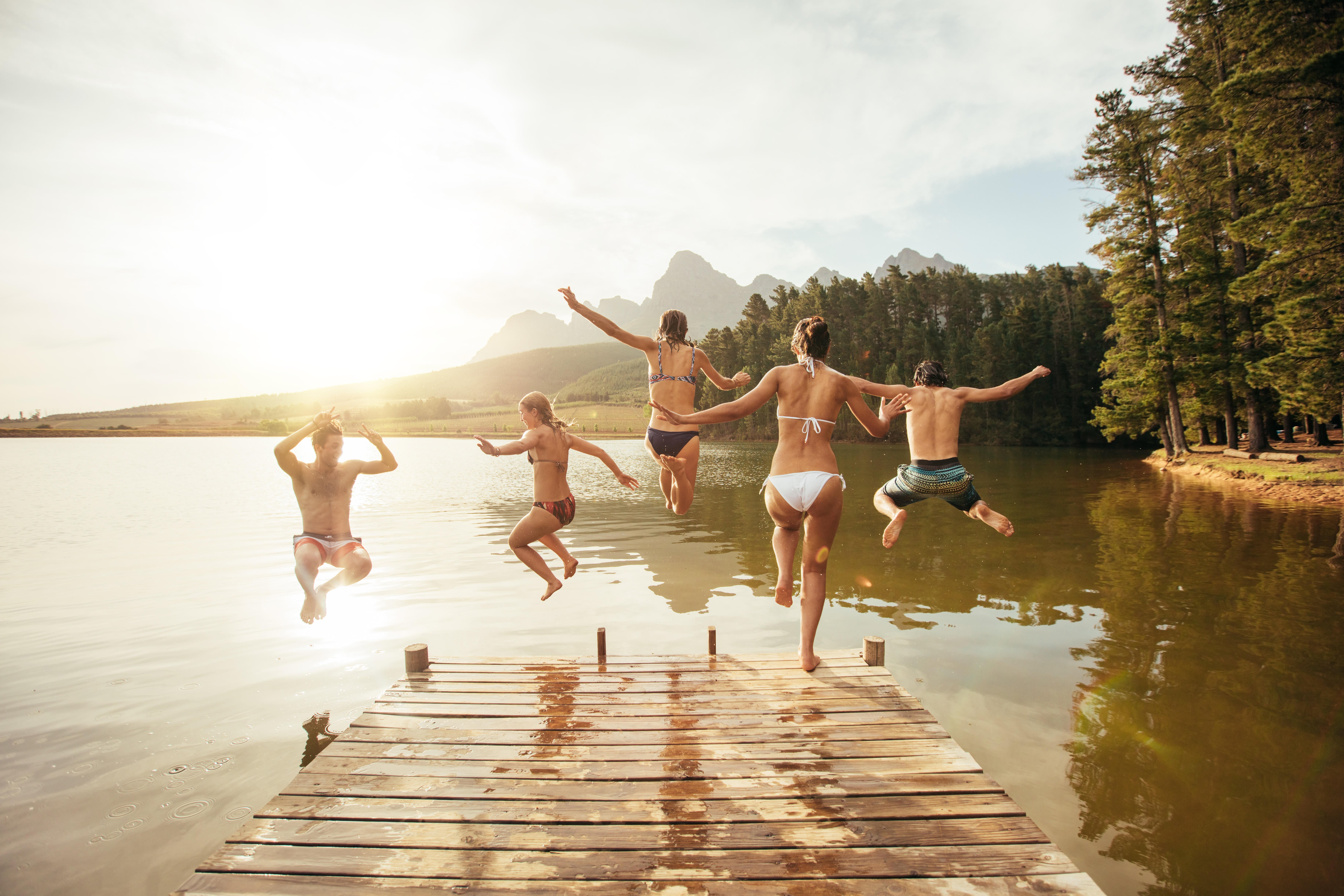 Friends leaping into a lake