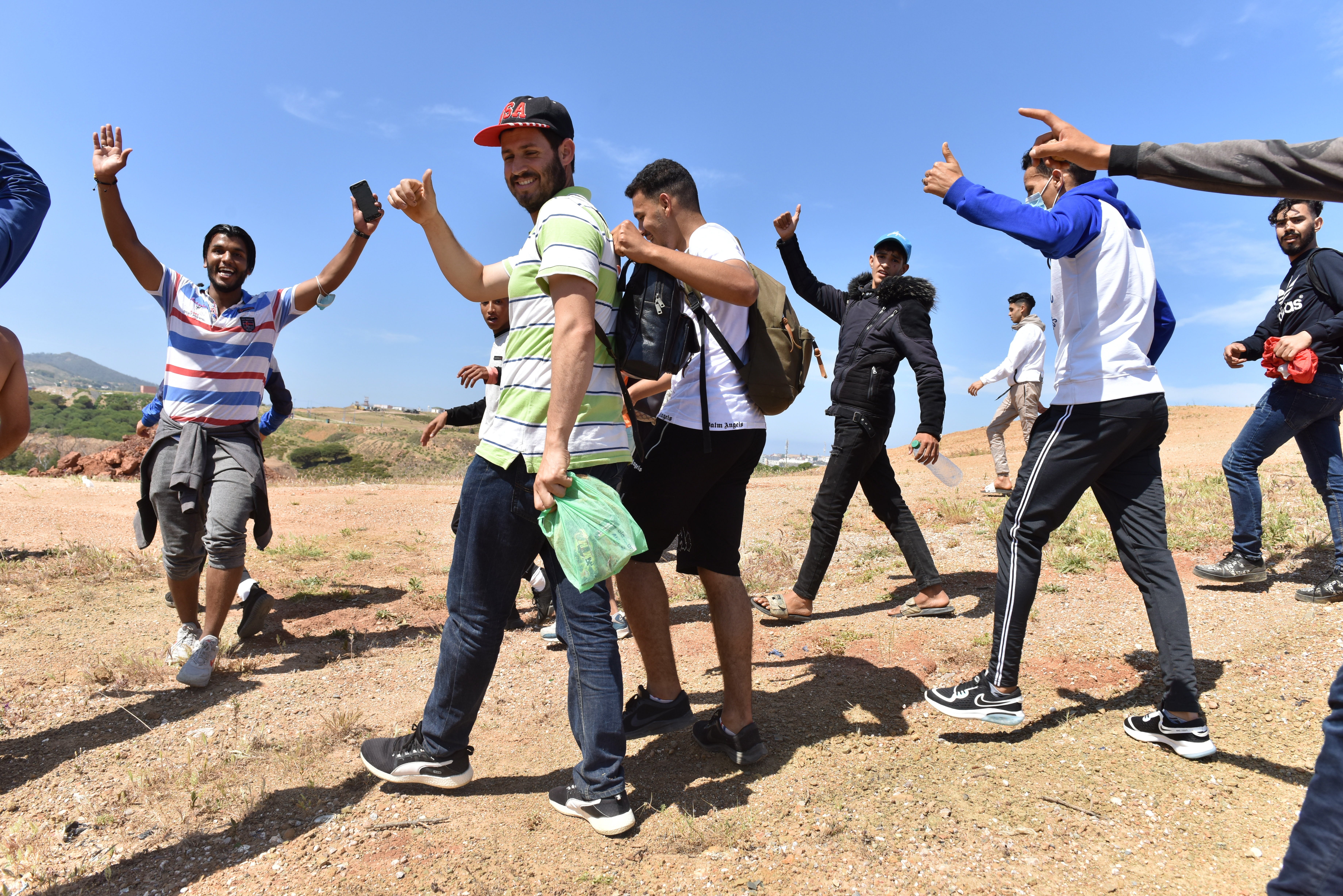 Migrants cheer as they walk towars the border posts in the northern Morocco town of Fnideq