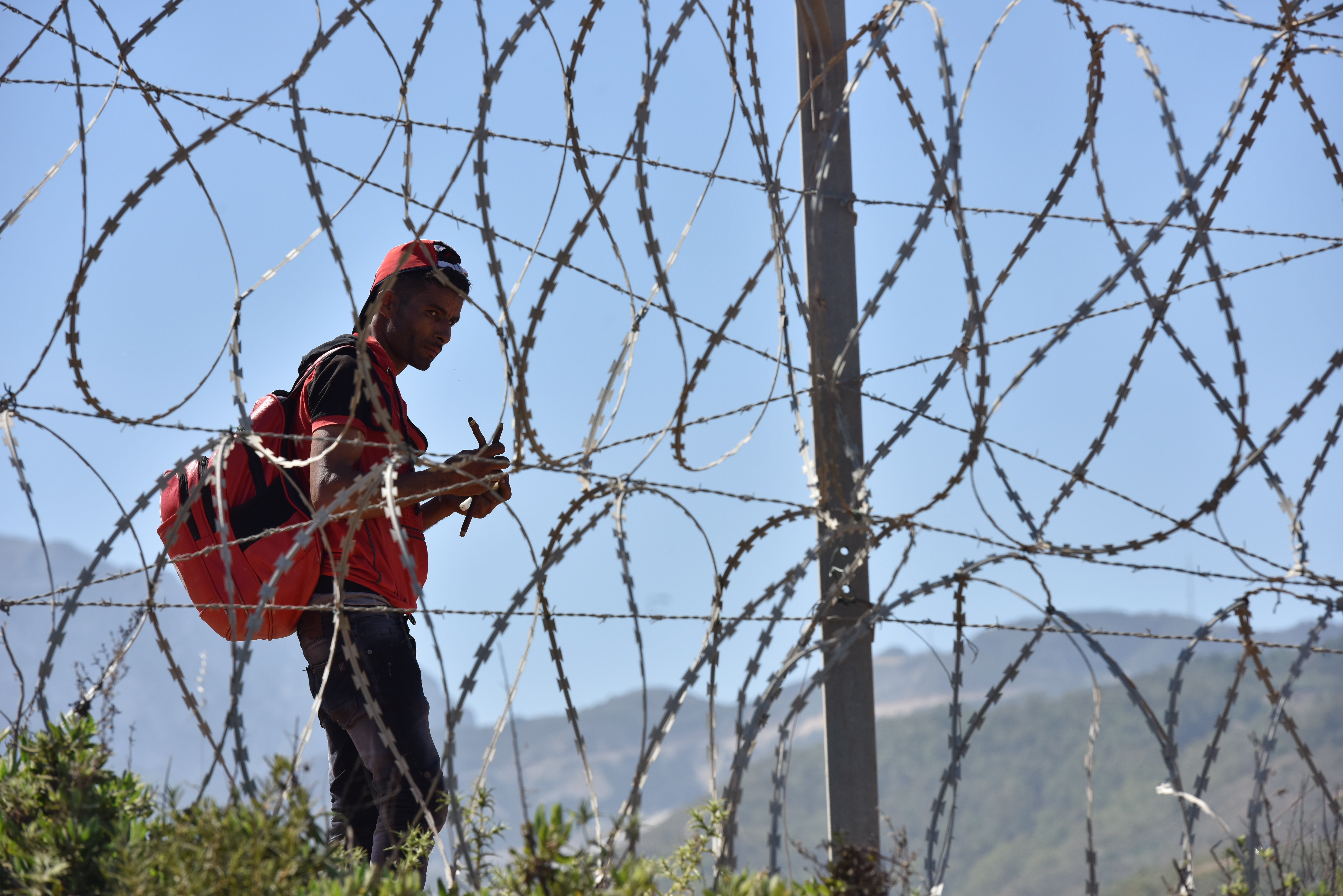 A migrant waits to sneak through the fence in the northern Morocco town of Fnideq in an attempt to cross the border to the Spanish enclave of Ceuta