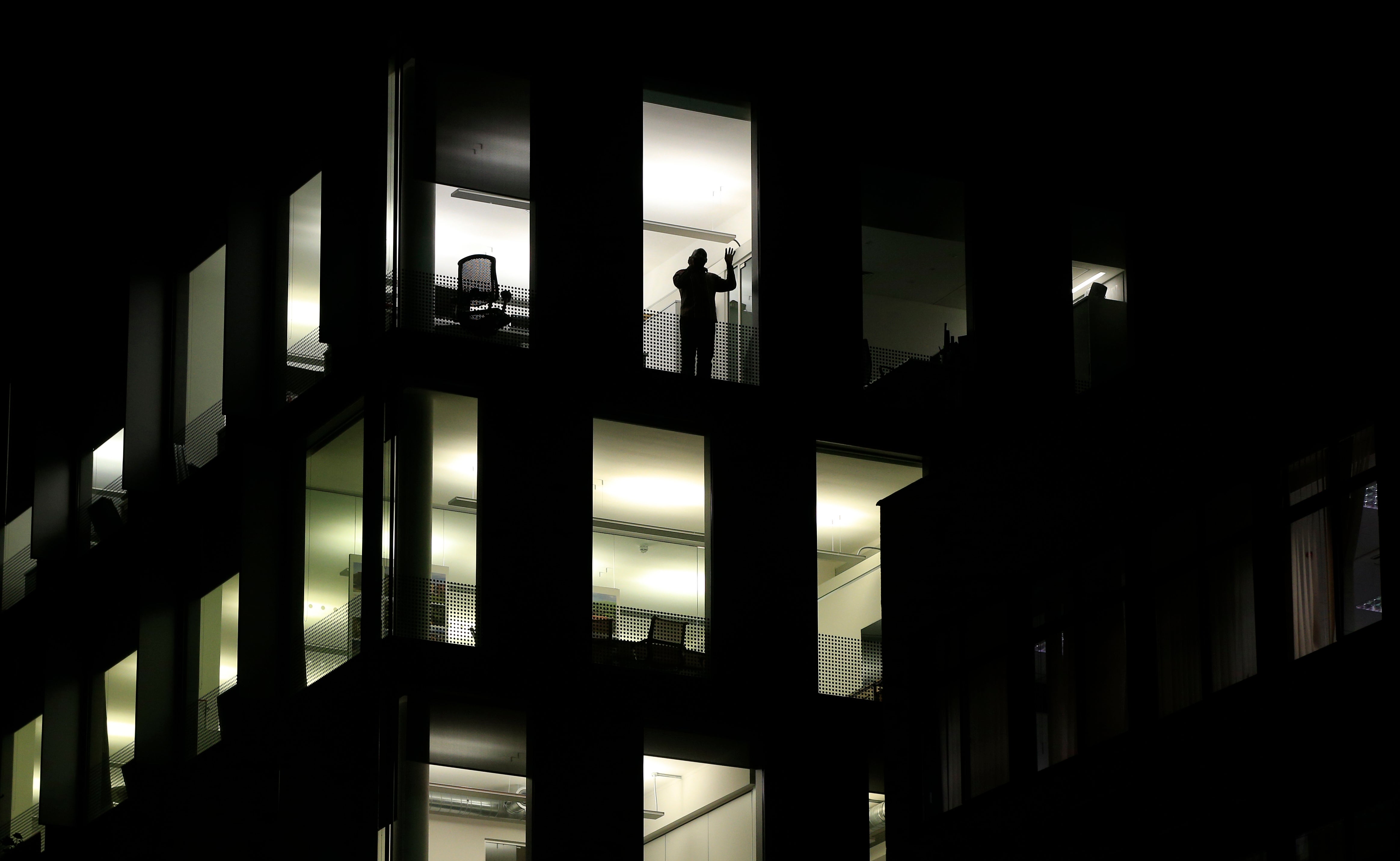 A solitary employee stands by a window in an otherwise empty office