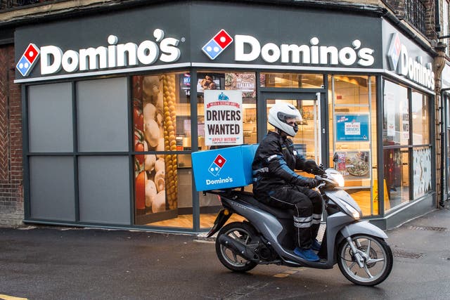 A delivery rider outside a branch of Domino’s Pizza