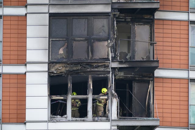 <p>Firefighters inspect damage to a 19-storey tower block in New Providence Wharf in London</p>