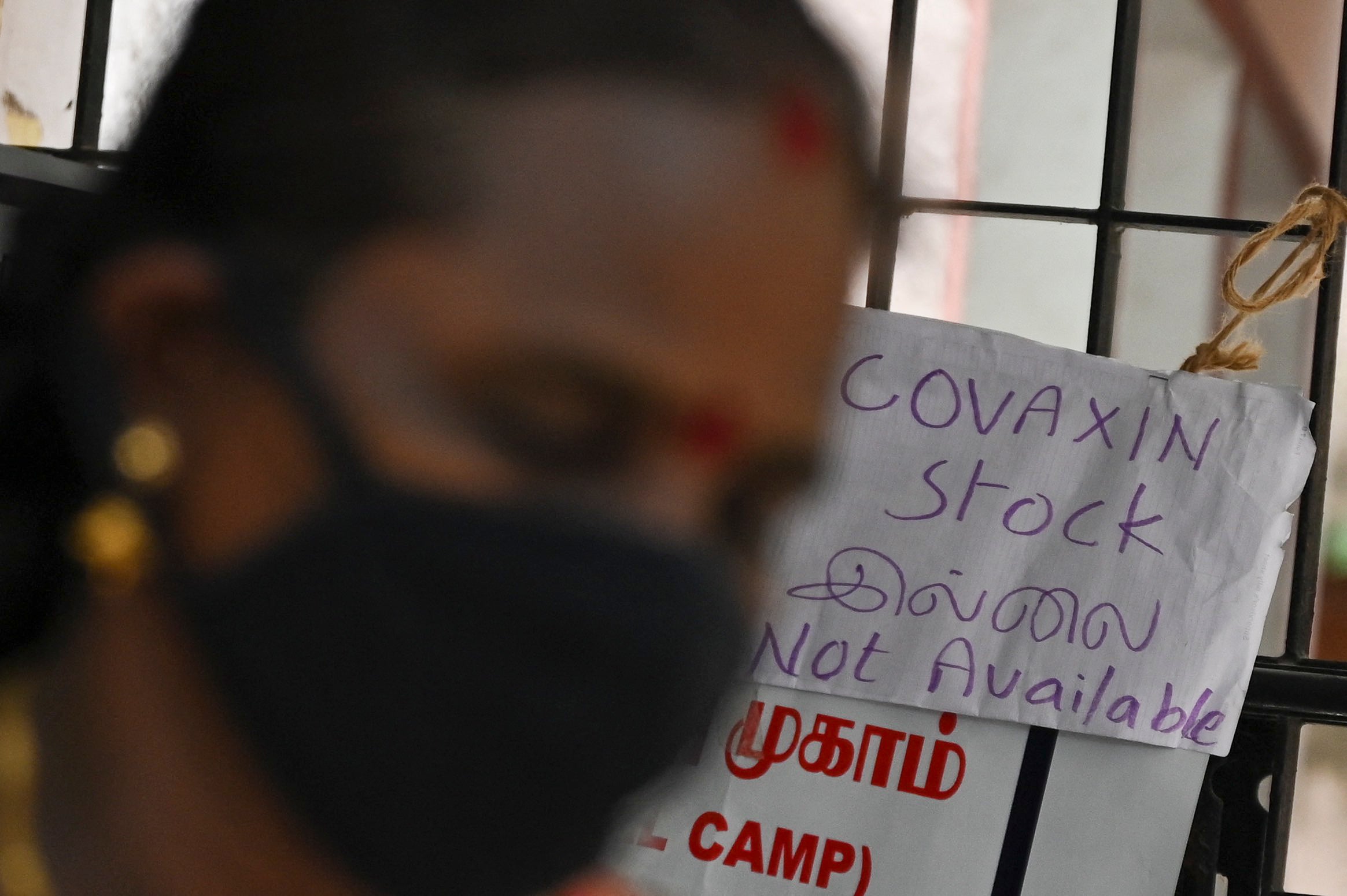 A woman walks past a notice announcing the unavailability of Covid-19 vaccine doses due to stock shortages