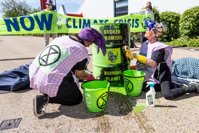 <p>Protesters remove paint from oil drums, symbolically washing away the ‘soothing promises peddled by the UK Government and fossil fuel industry’</p>