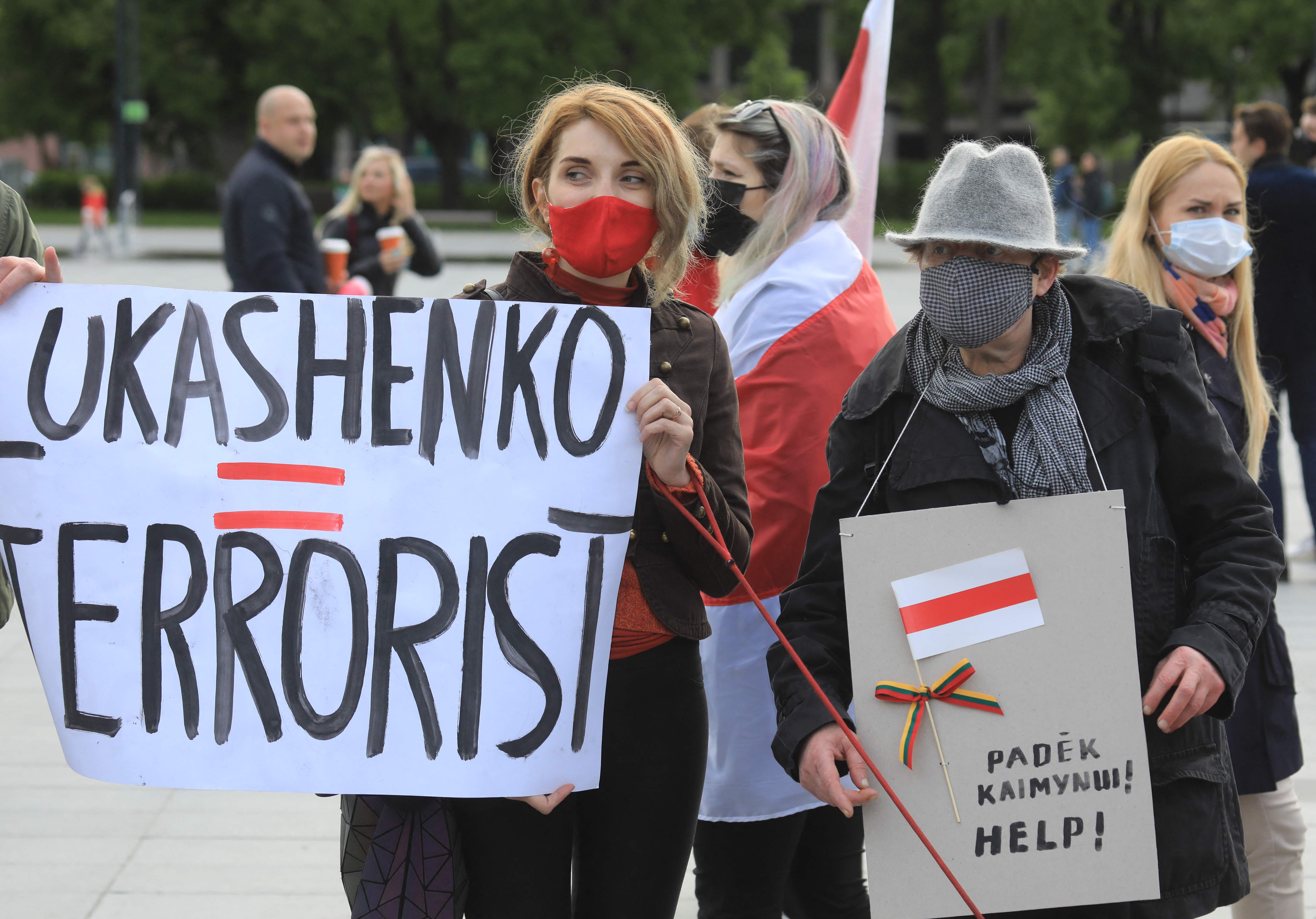 Protesters hold placards and traditional Belarusian flags, the symbol of the opposition, in a demonstration against repression in Vilnius