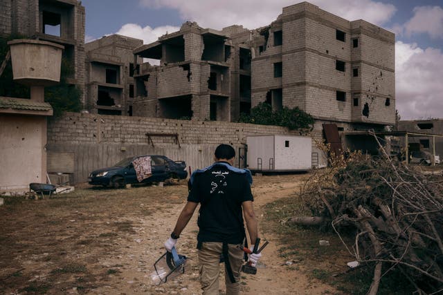 <p>Mohammed Zlateni approaches the area where an unexploded artillery shell is buried near a house in Tripoli</p>