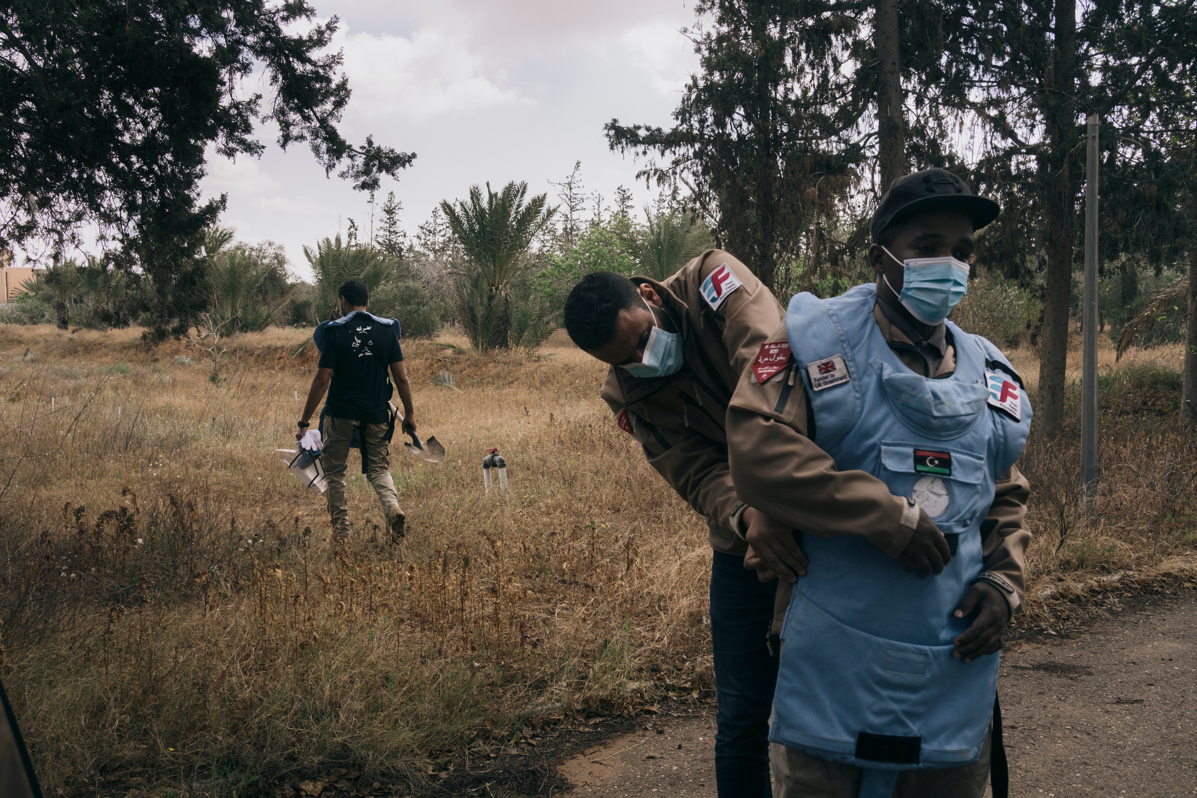 Mohammed Zlateni, left, and his colleagues at the Free Fields Foundation, prepare to collect an unexploded mortar round from a field in the suburbs of Tripoli