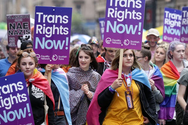 <p>Personas que portan pancartas de derechos trans participan en el desfile del Orgullo en Glasgow</p>