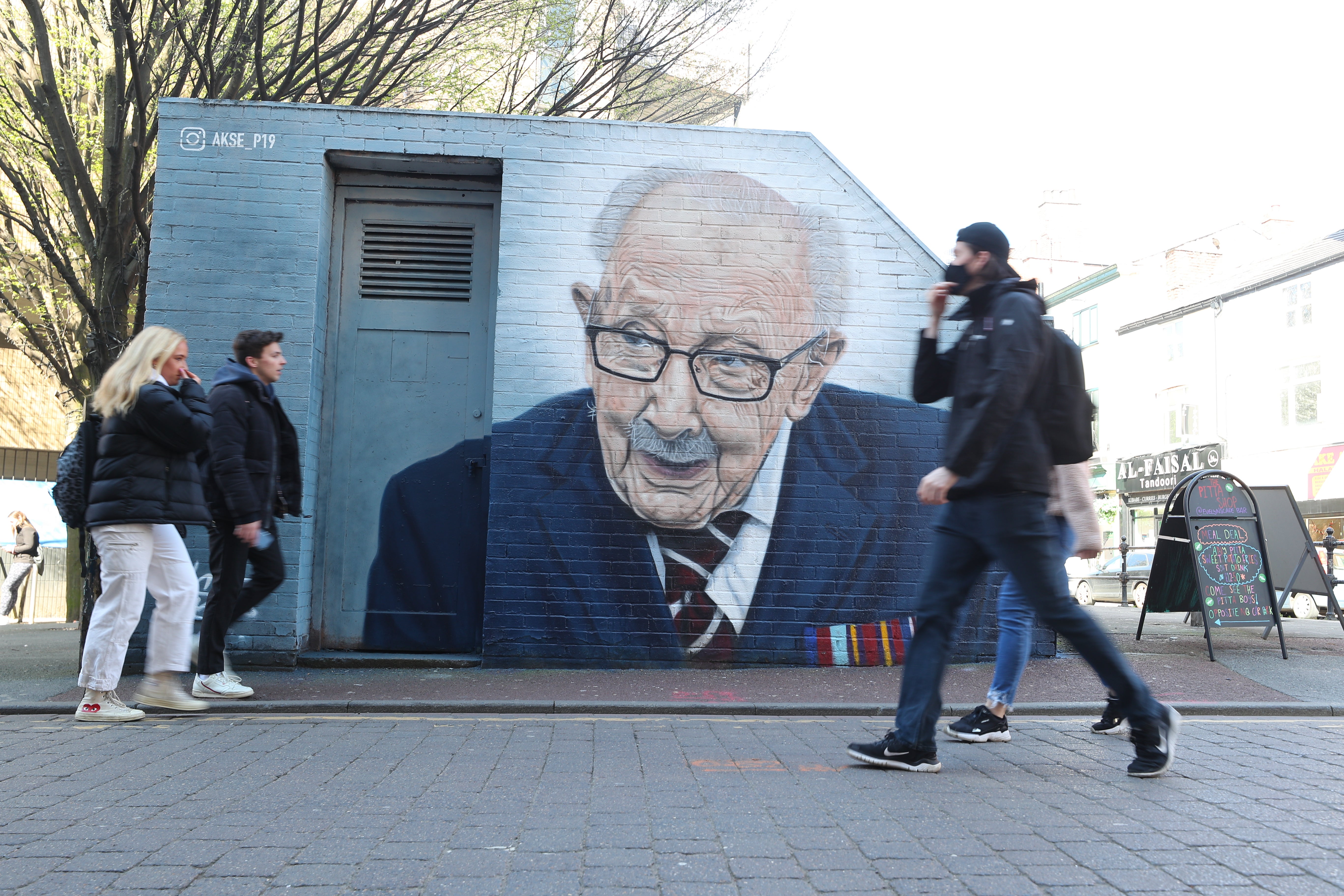 People walk past a mural of Captain Sir Tom Moore by by Street artist Akse P19 in Manchester's North Quarter