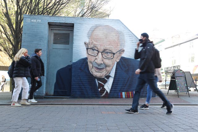 <p>People walk past a mural of Captain Sir Tom Moore by by Street artist Akse P19 in Manchester's North Quarter</p>