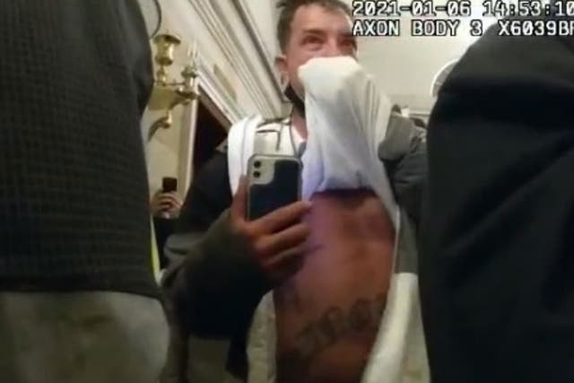 <p>James Burton McGrew lifts his shirt while participating in the Capitol riot on 6 January</p>